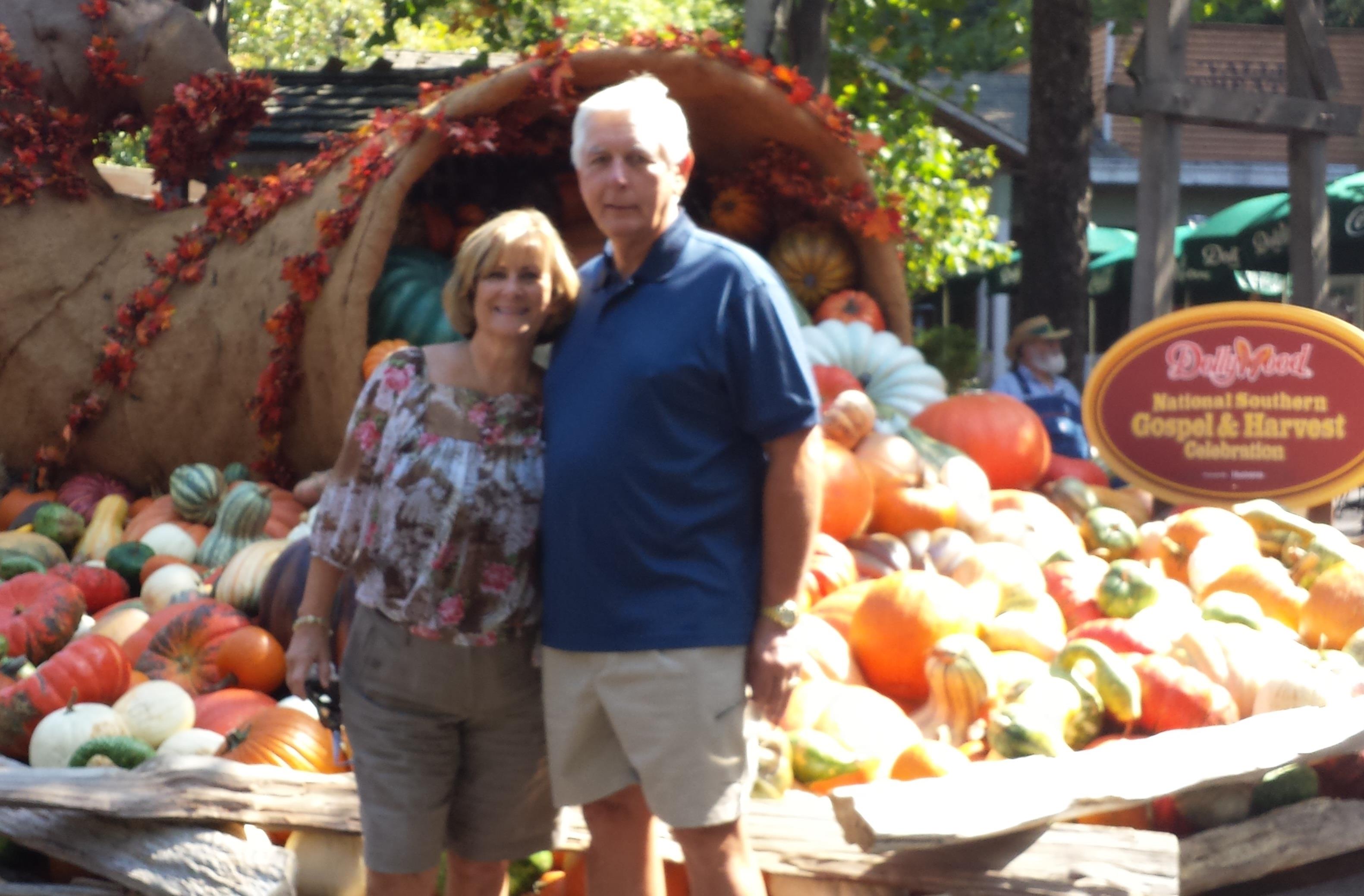 A man and woman standing in front of a pumpkin display