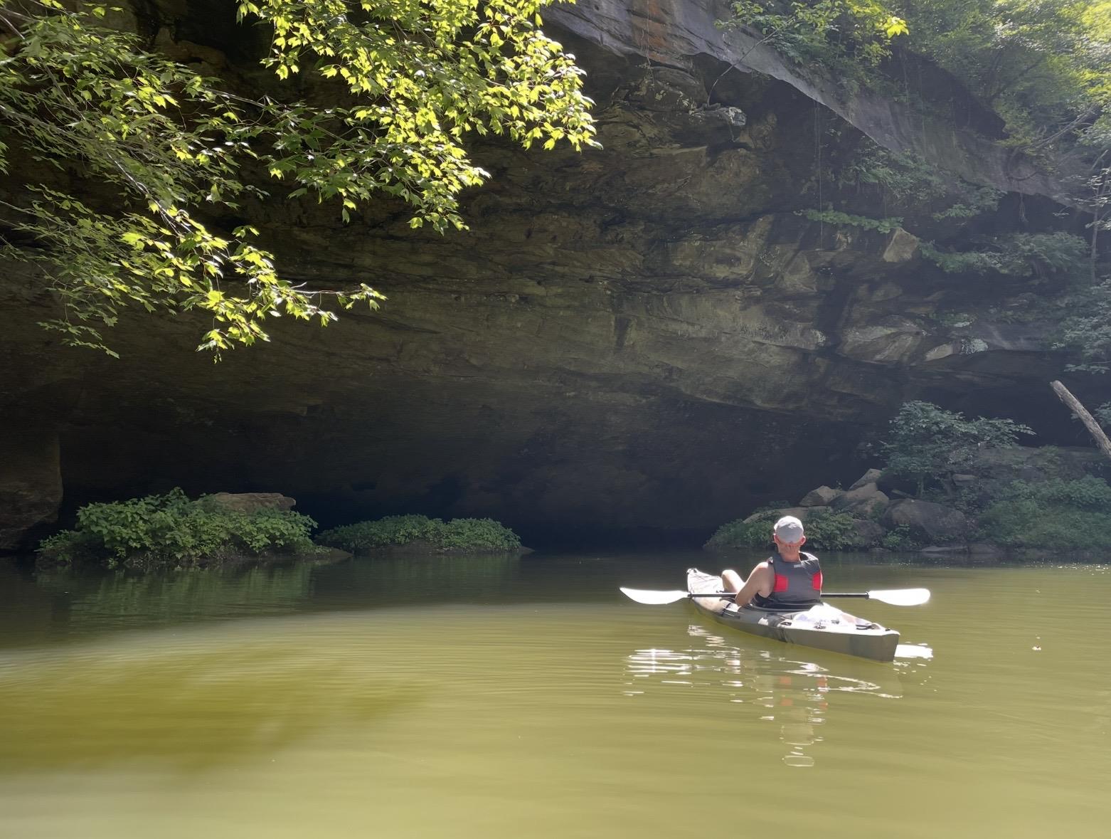 A person in a kayak under a cave