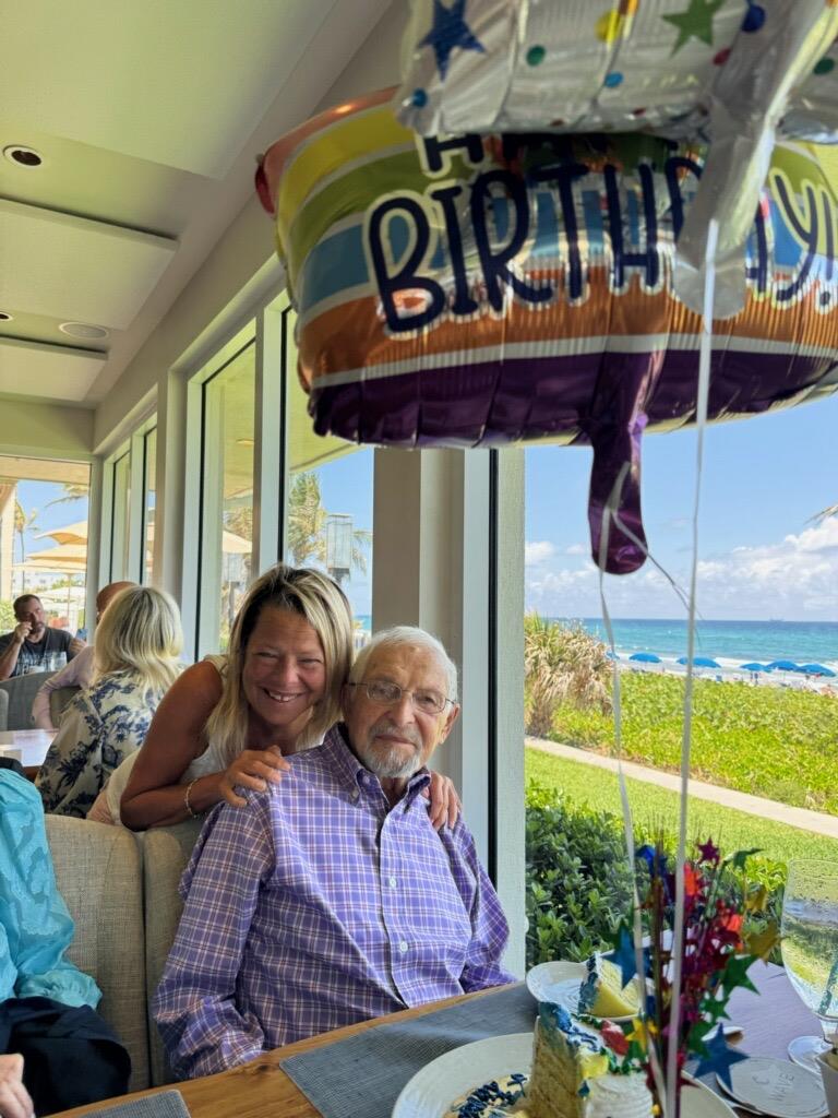 A man and woman sitting at a table with a balloon
