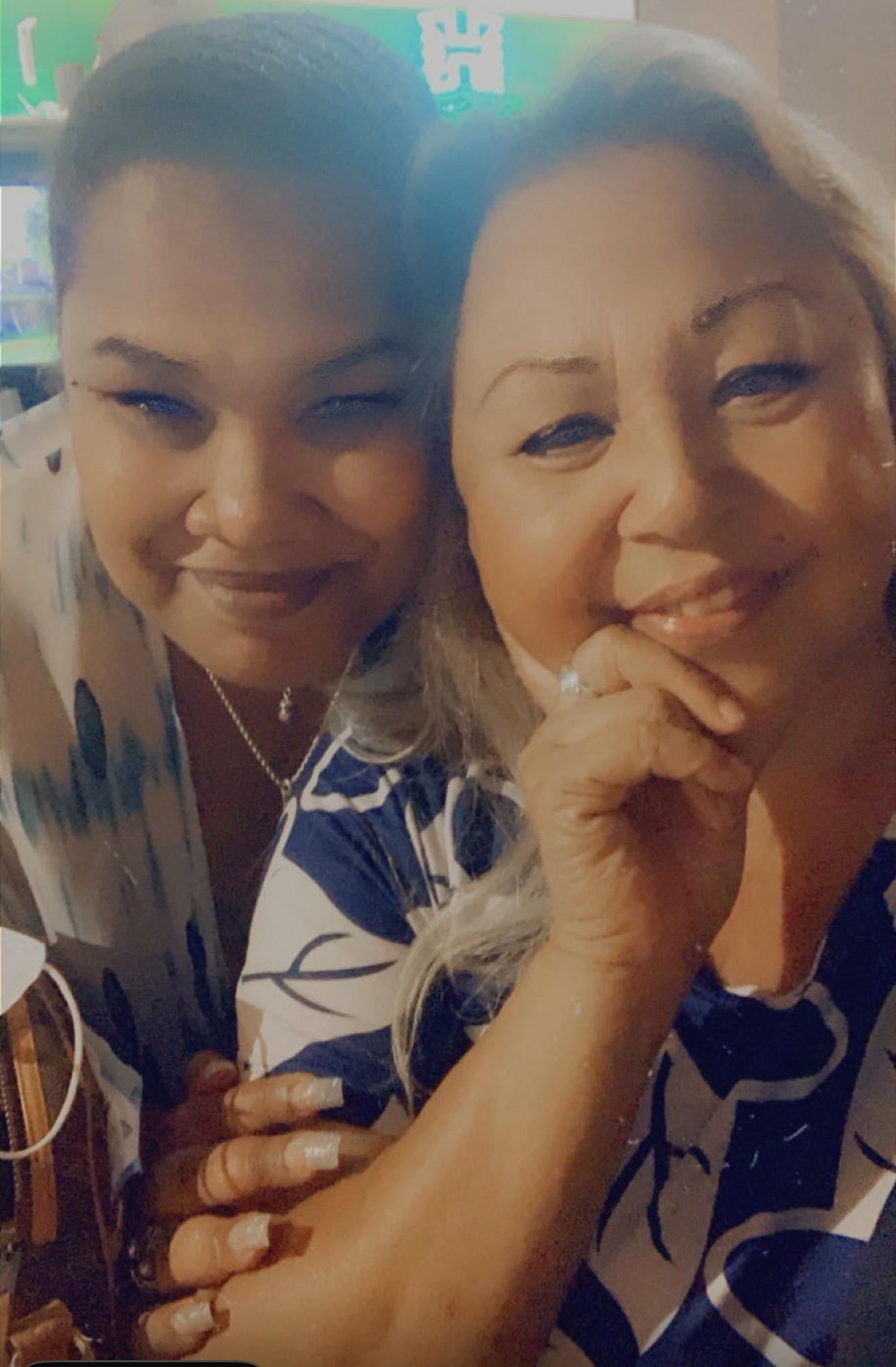 Two women pose for a selfie, sharing a moment of joy while dining together at a restaurant.