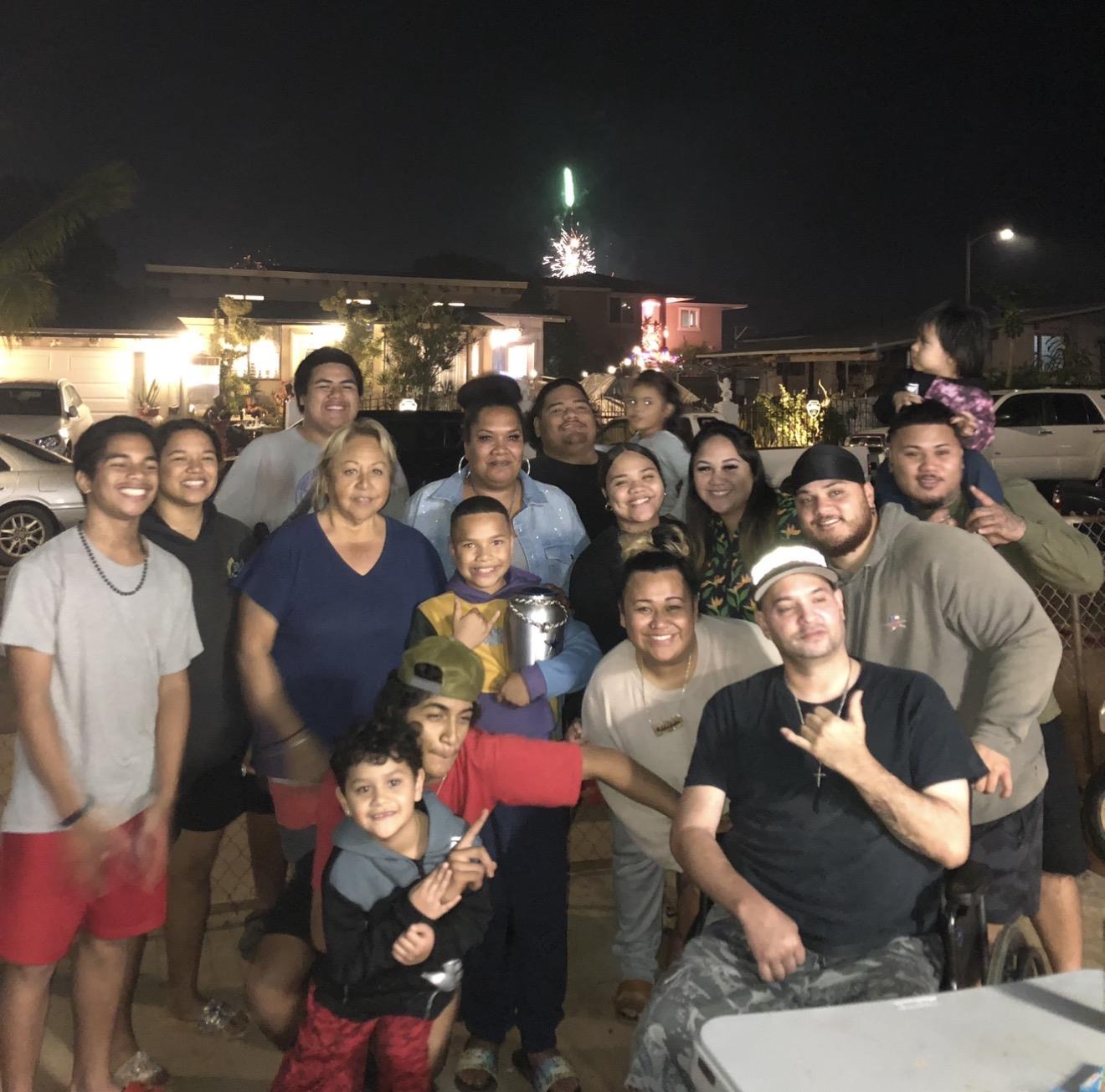 People gather and pose for a photo during a night celebration in the backyard.
