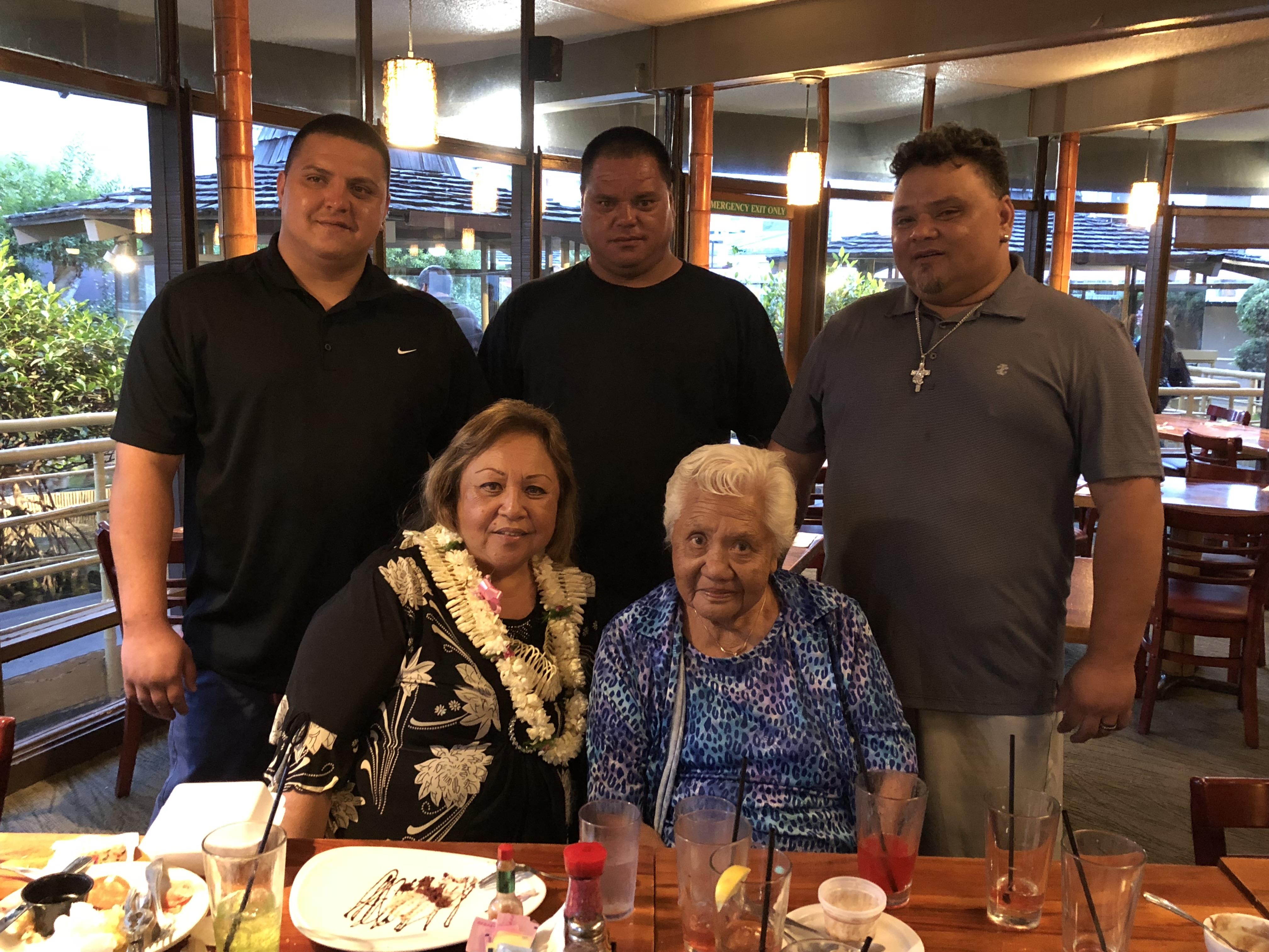 Five family members enjoy a meal together at a restaurant in the evening time.