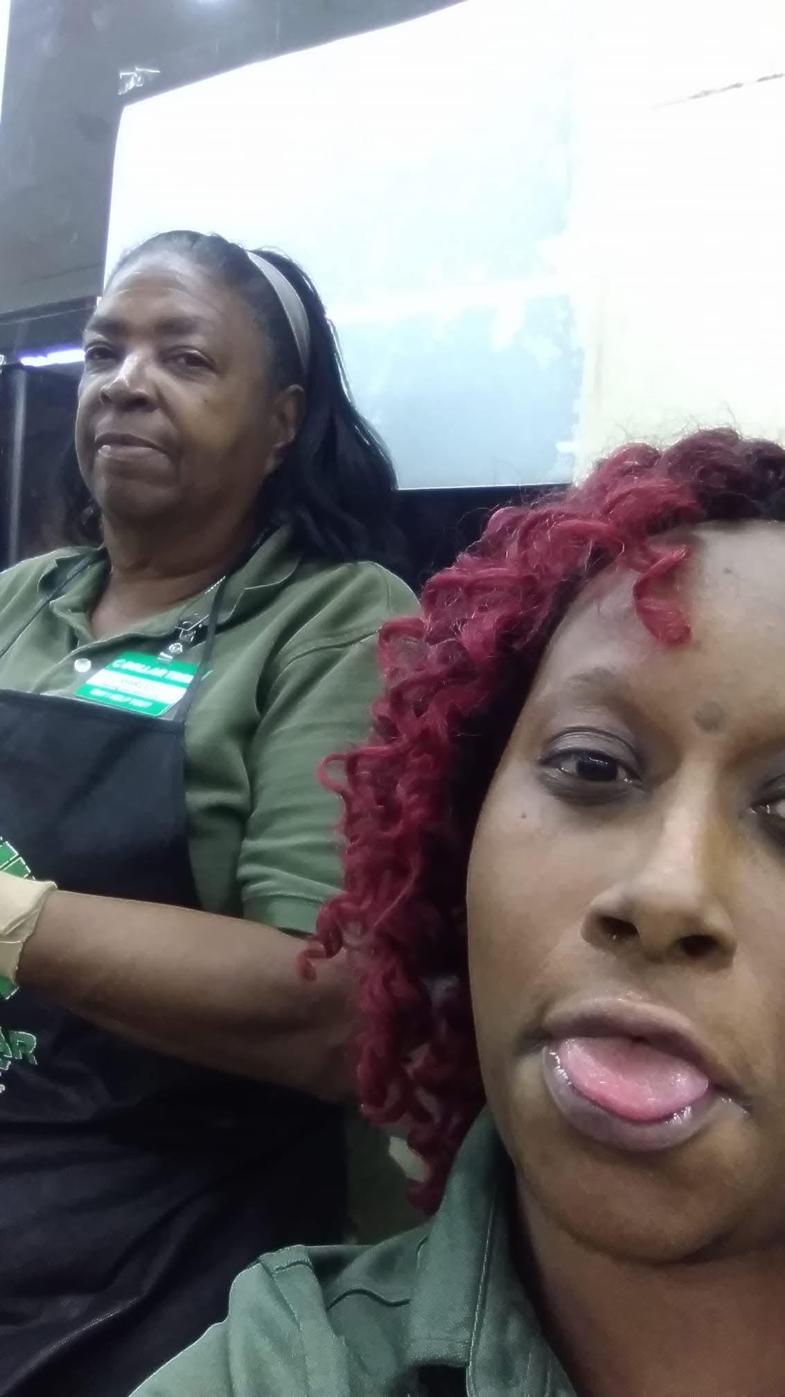 Two women are taking a self-portrait at a store. One woman is smiling while the other looks serious.