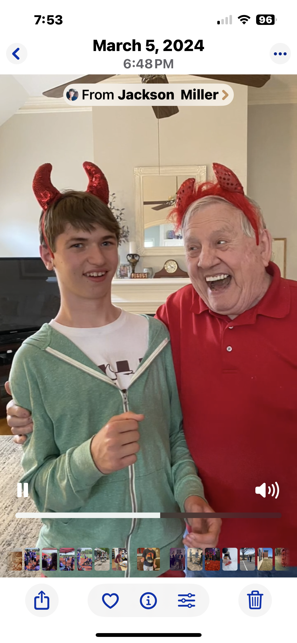 Two people smile and share a joyful moment in a cozy living room while wearing playful hats.