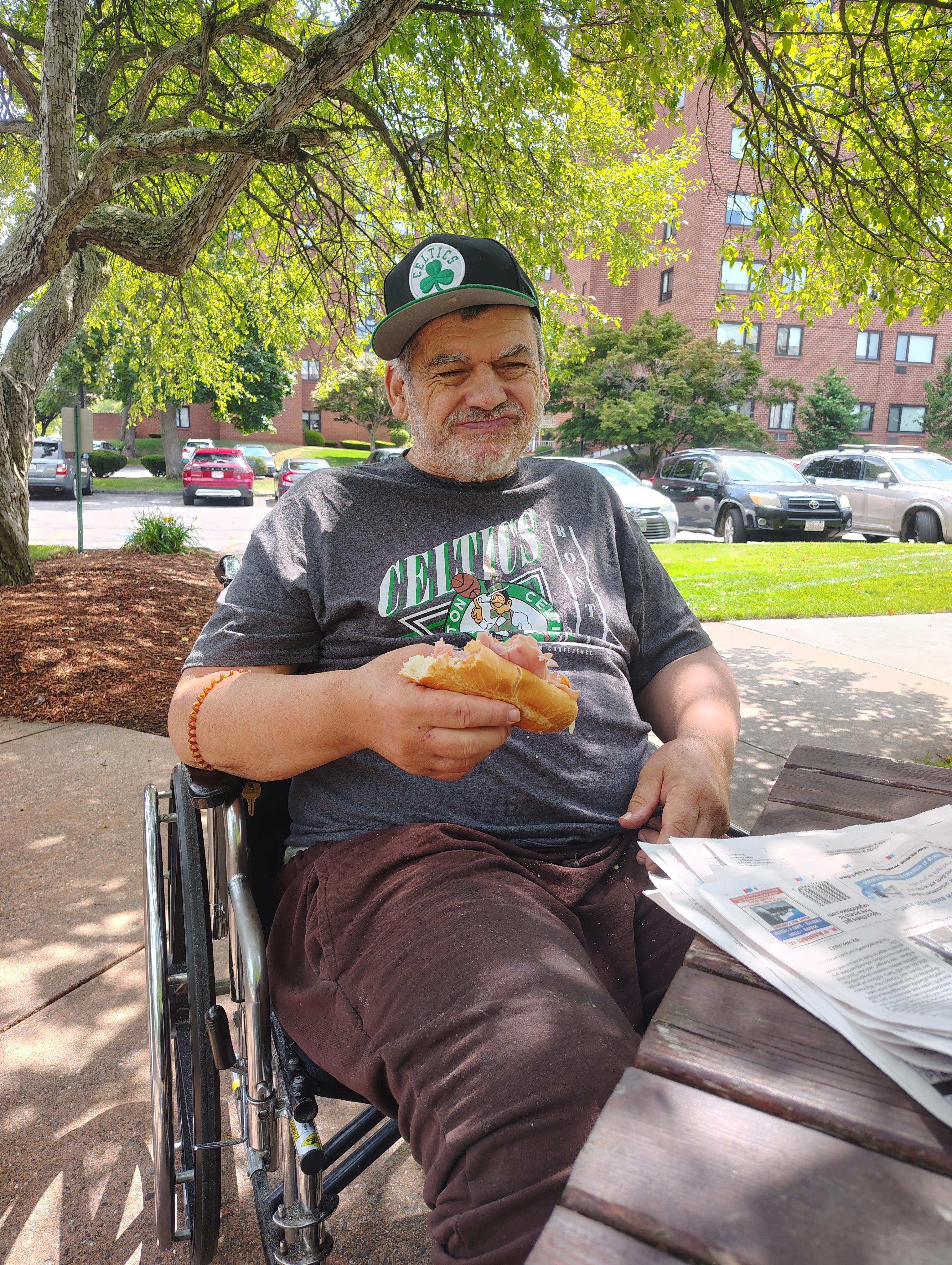 A man in a wheelchair eating a sandwich