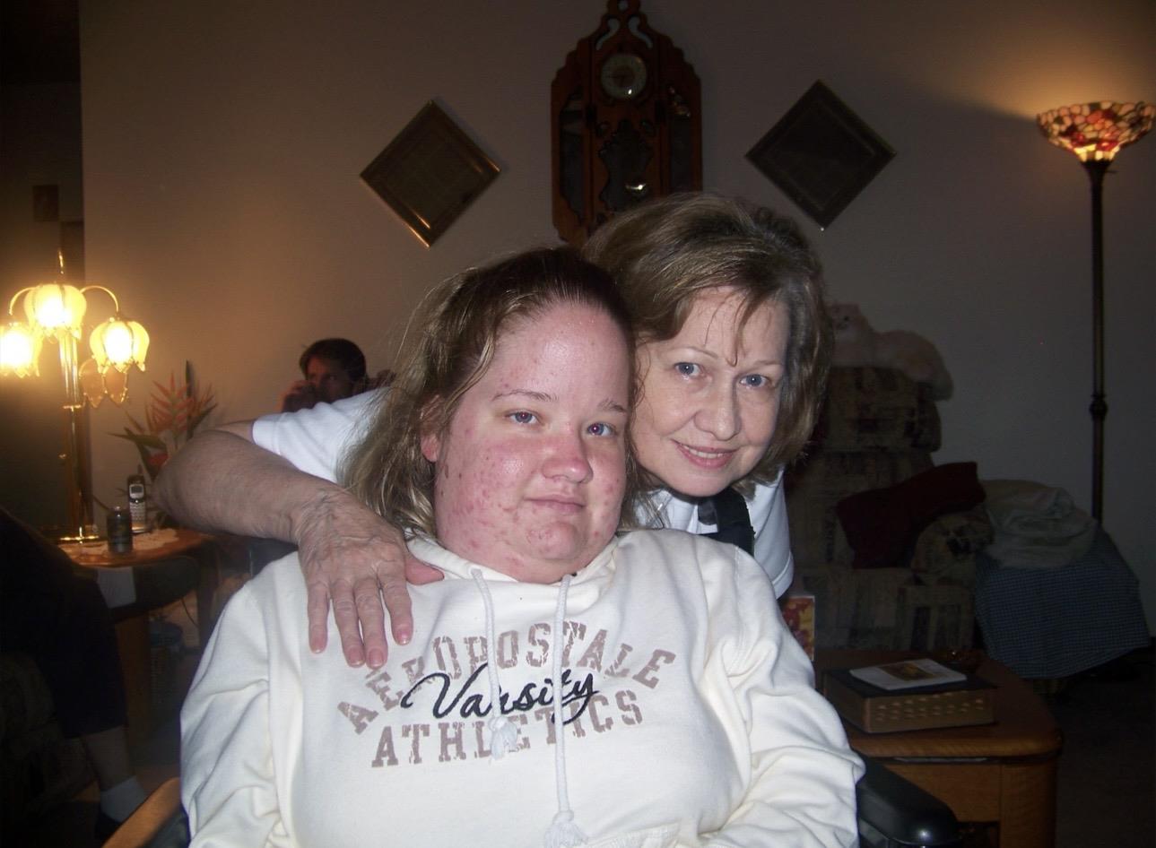 Two women are smiling and enjoying each other's company in a cozy indoor setting.