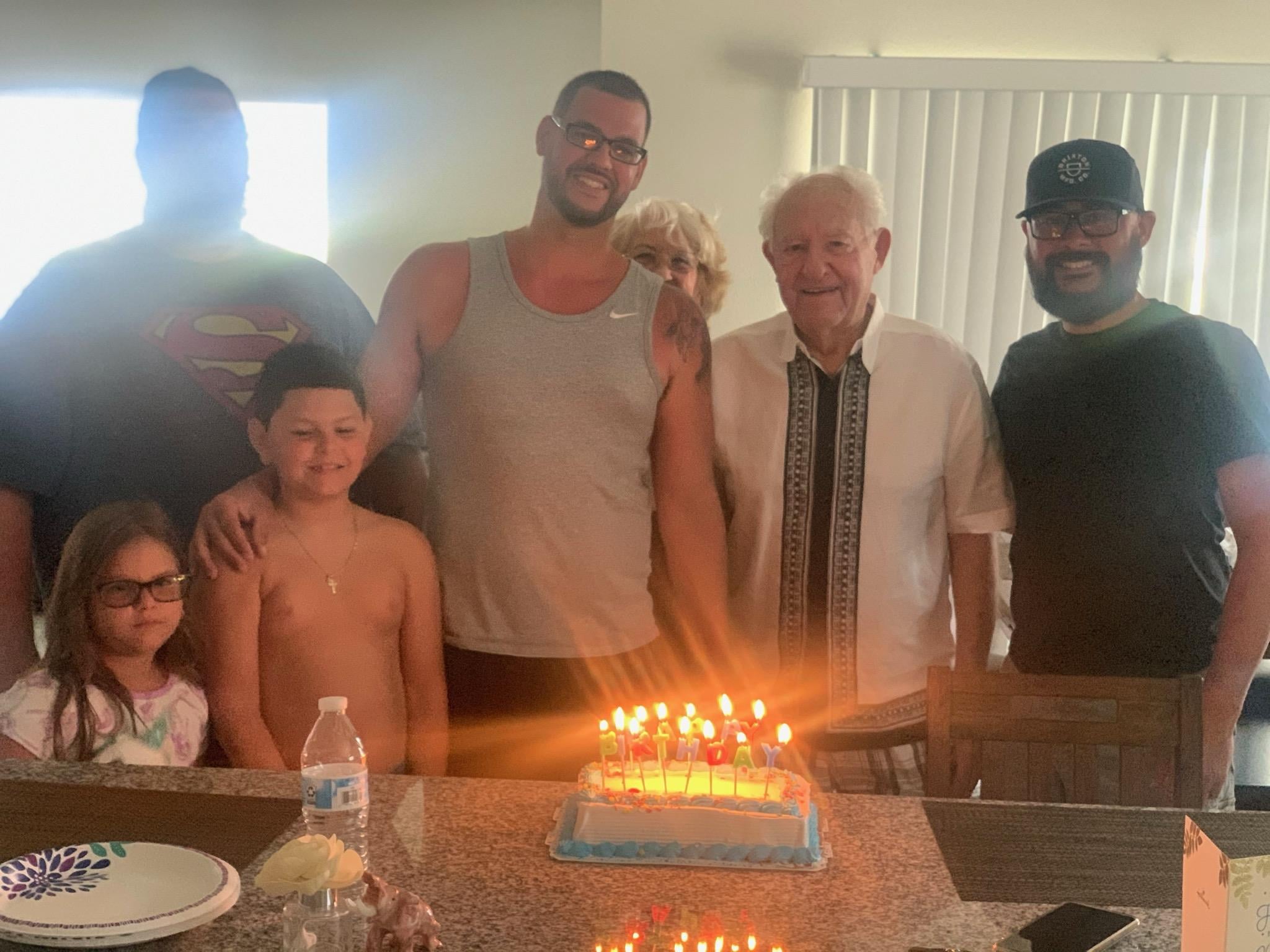 A group of people standing around a birthday cake