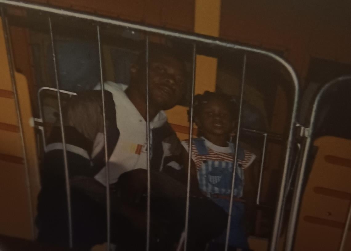 A group of people sitting behind a metal fence