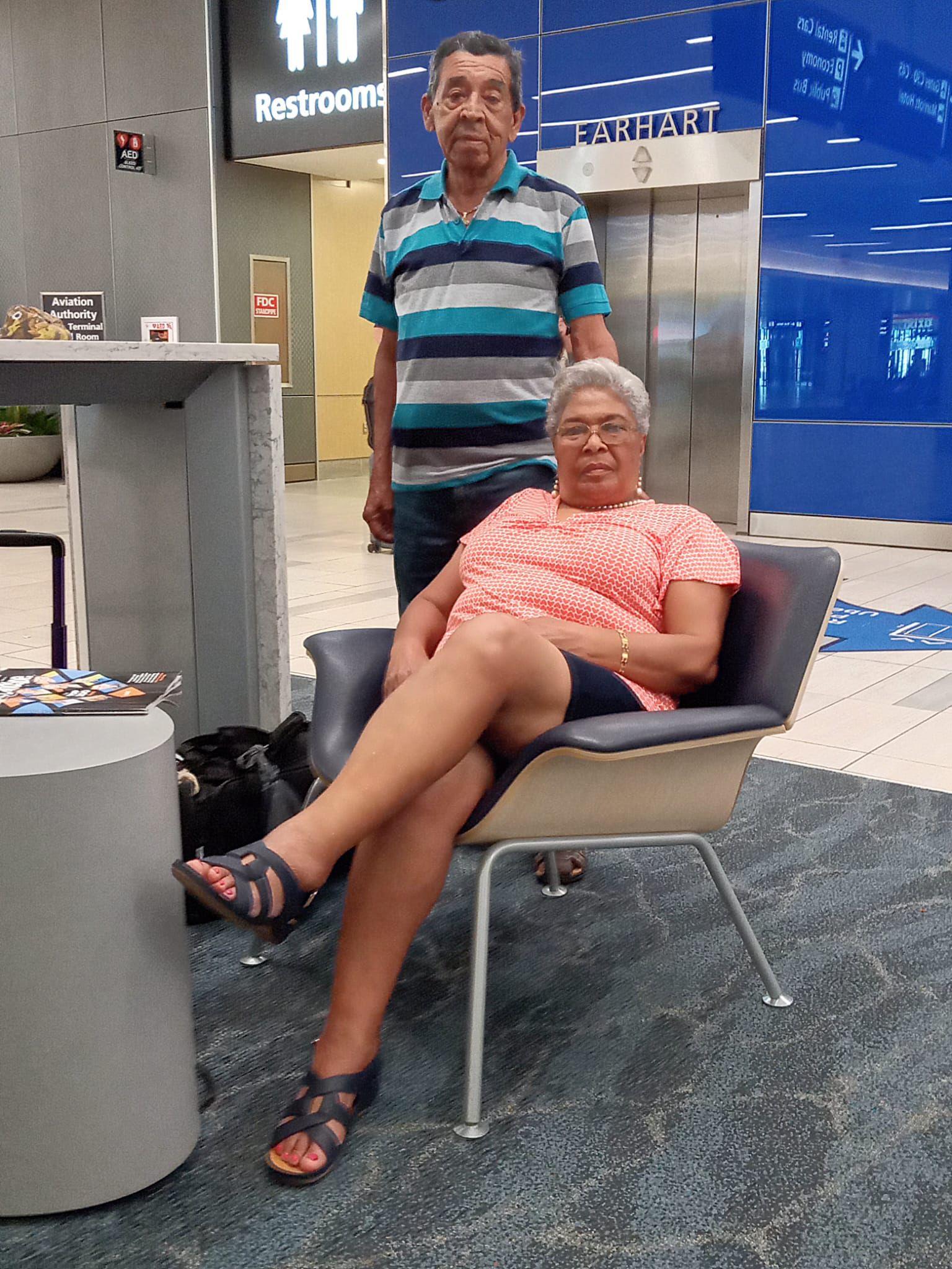A man standing next to a woman sitting in a chair