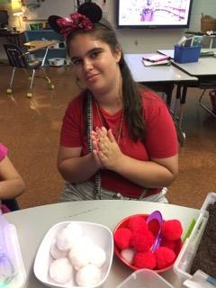 A girl sitting at a table with her hands together