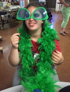A girl wearing a green boa and glasses