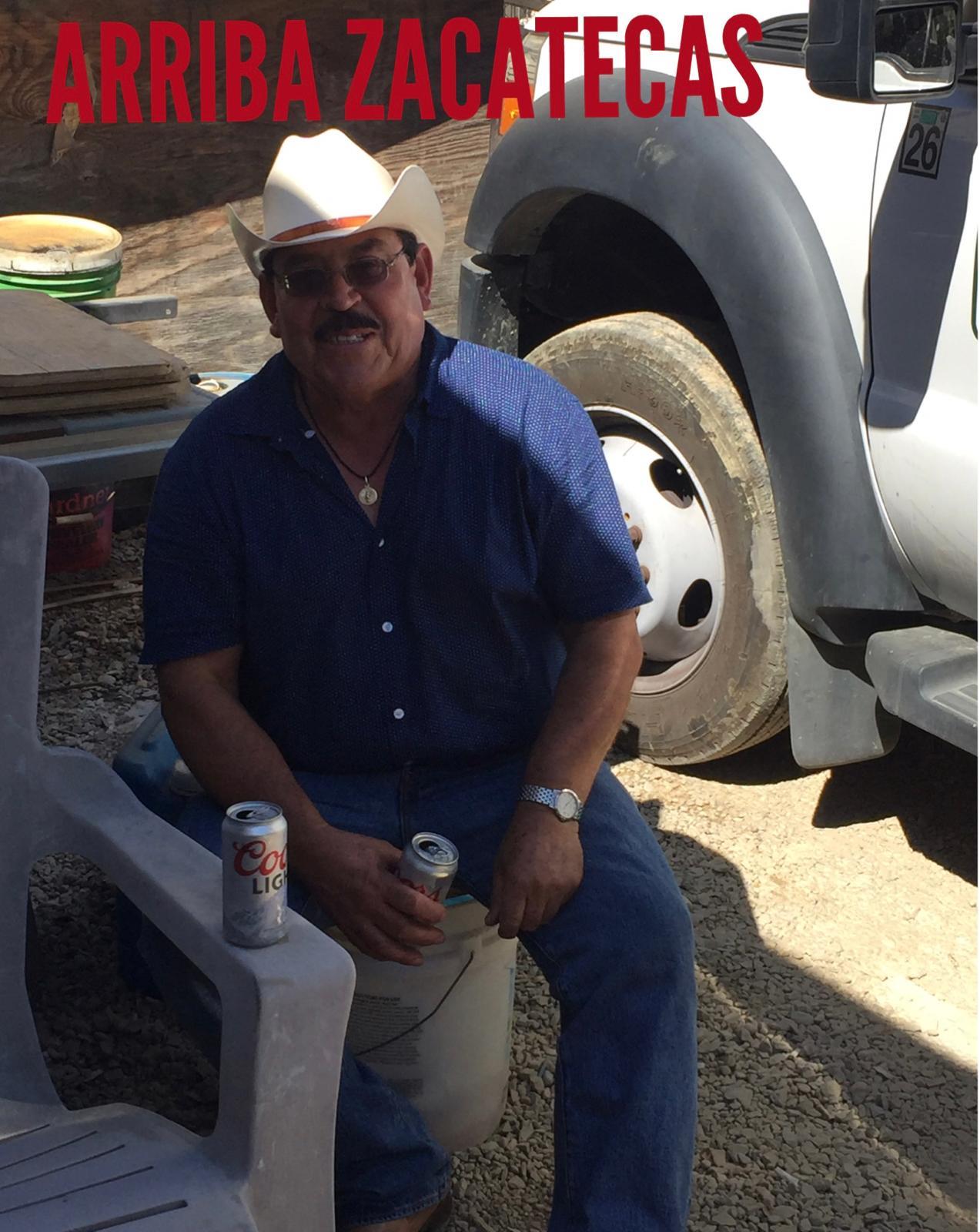 A man sitting on a white plastic chair with cans of beer