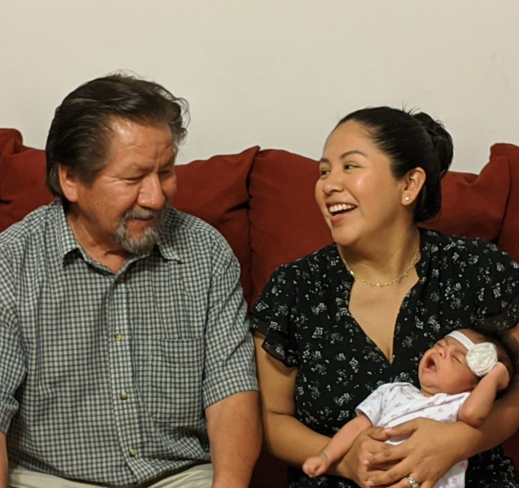A man and woman sitting on a couch holding a baby