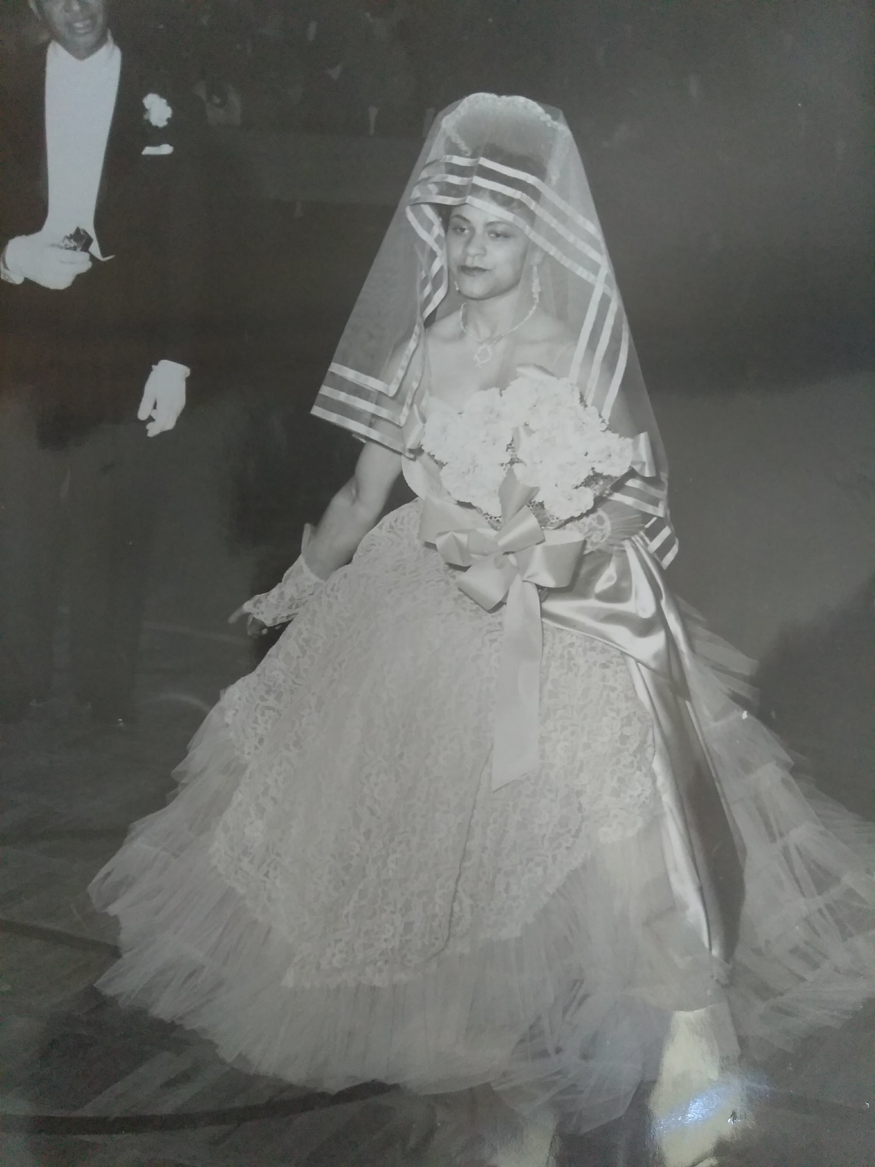 A young girl in a formal dress walks with a bouquet at a nighttime event.