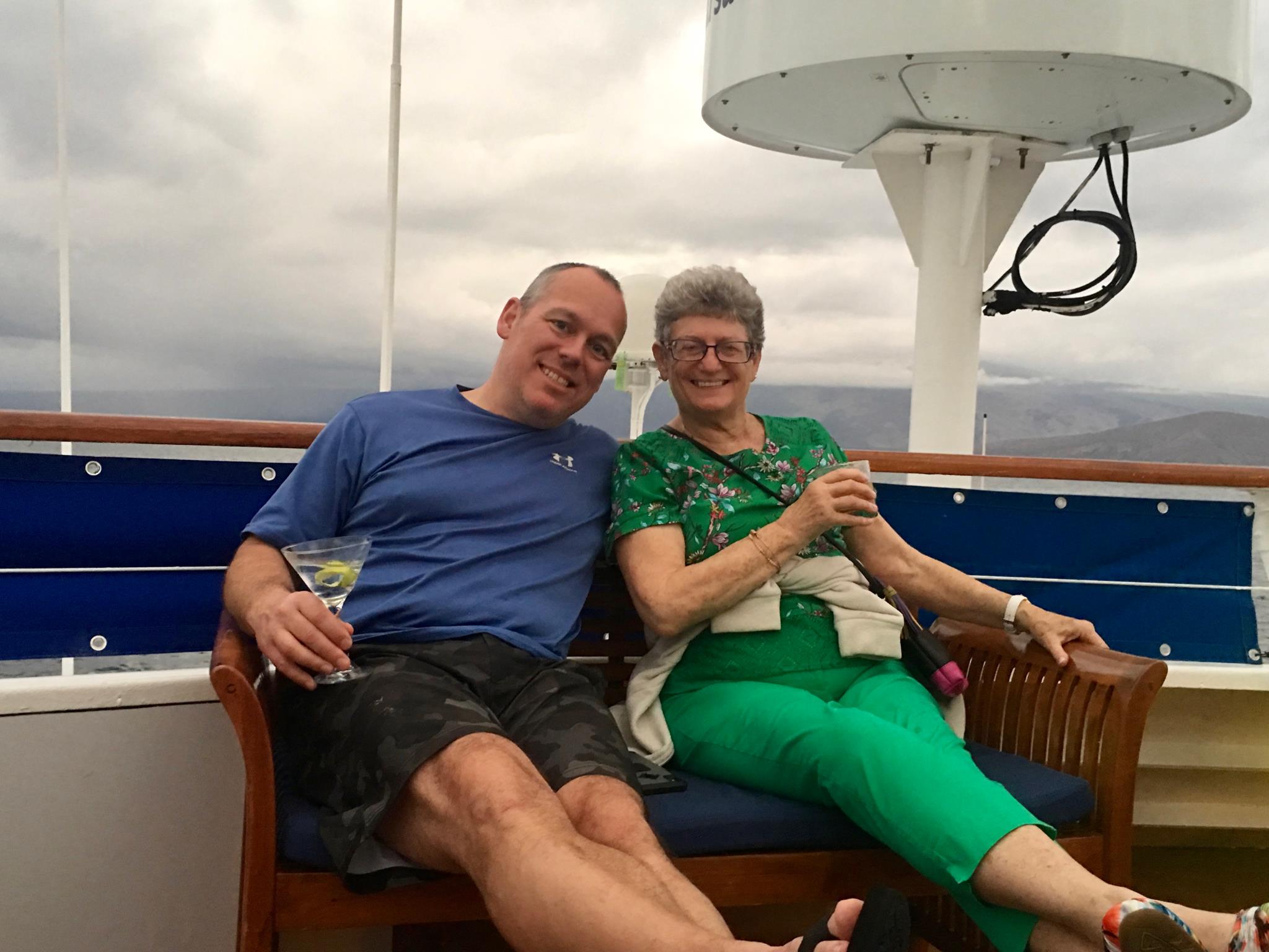 A man and woman sitting on a bench with drinks