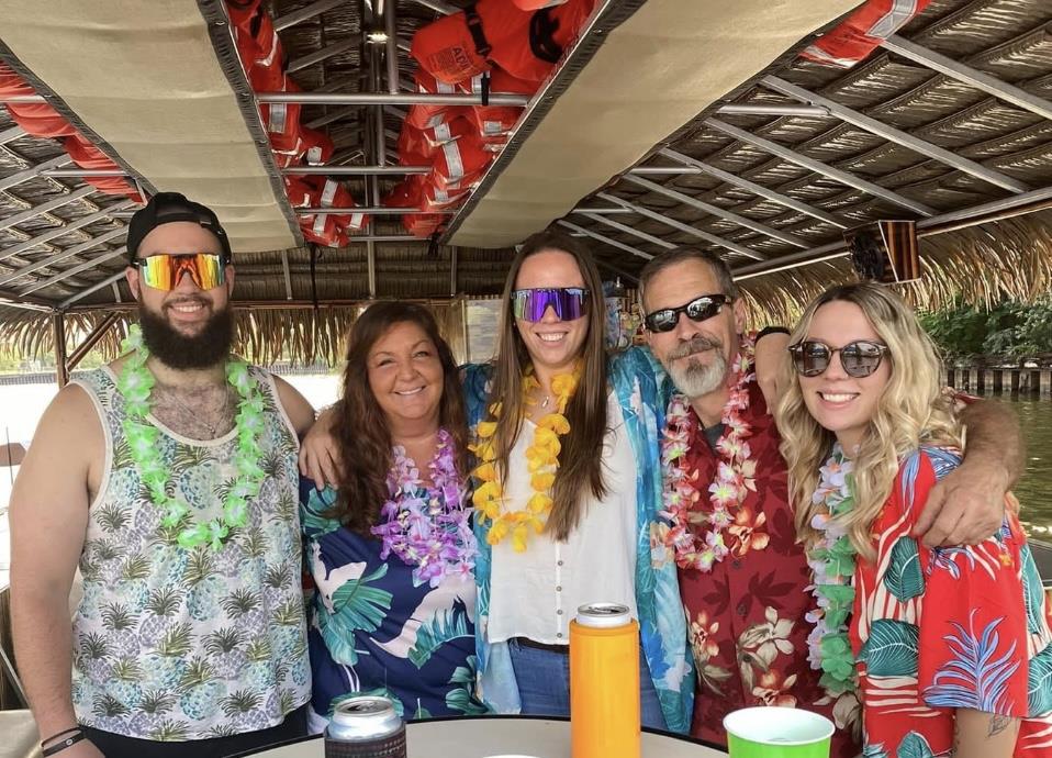 Friends enjoy time together on a boat with tropical decorations and a festive atmosphere.