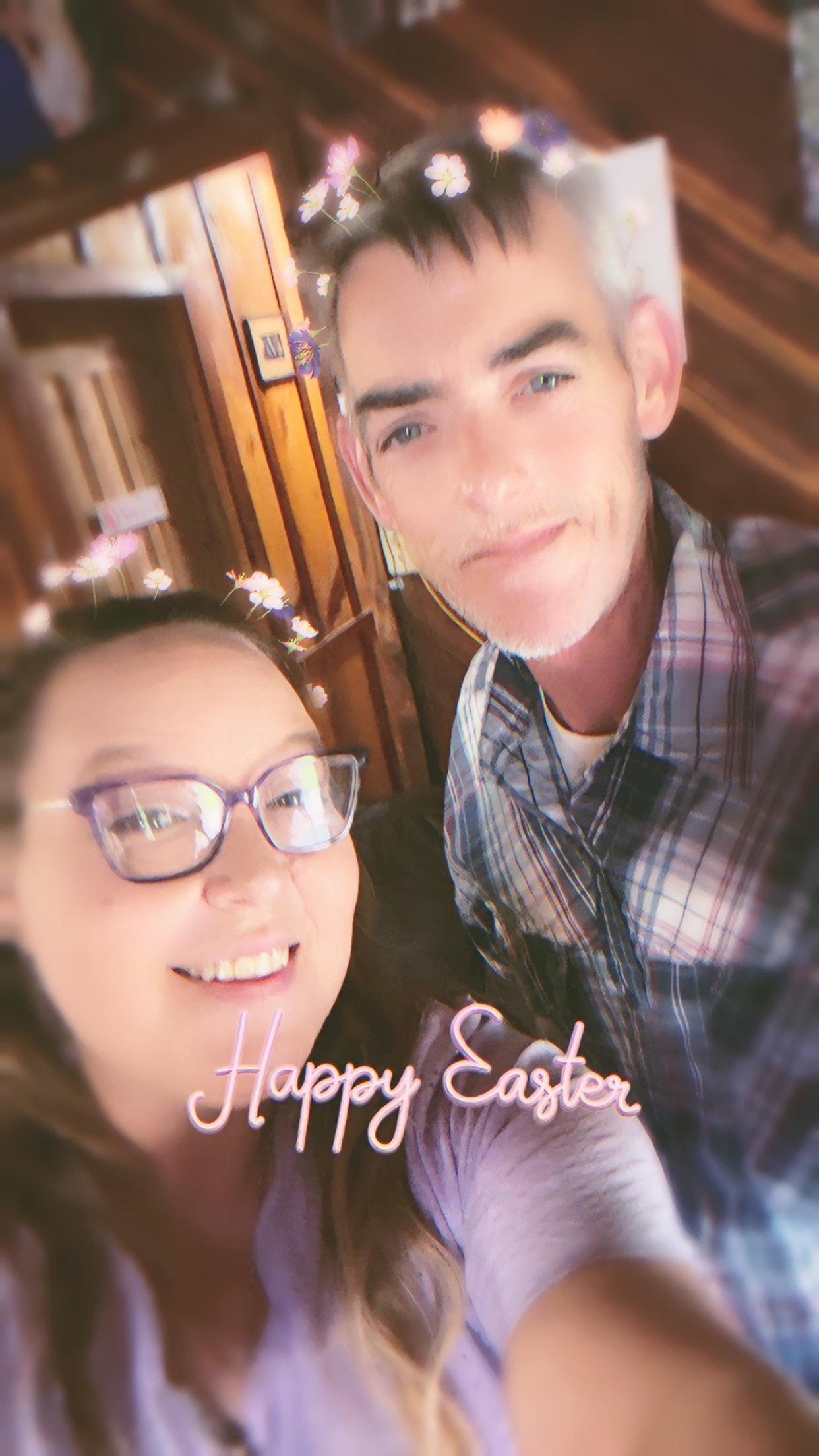 A couple poses together for a selfie inside a venue while celebrating Easter during the day.