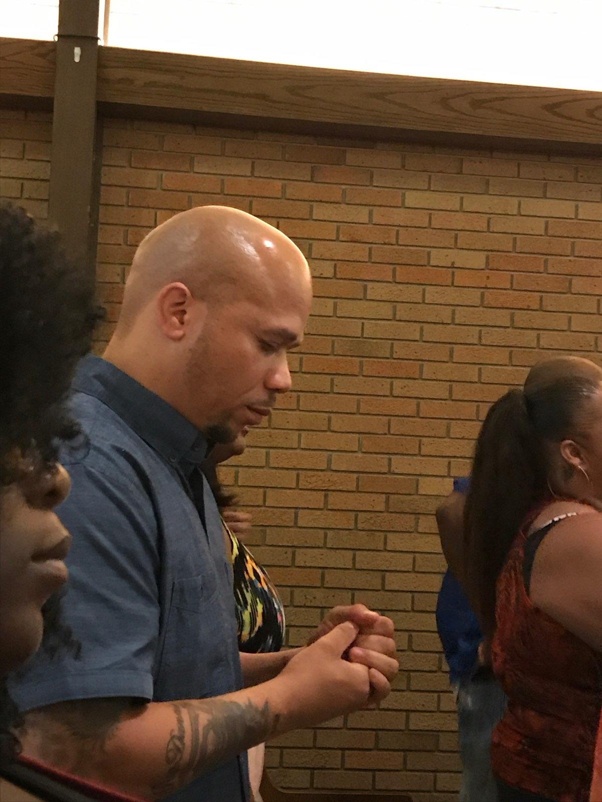 A man with bald head and hands together