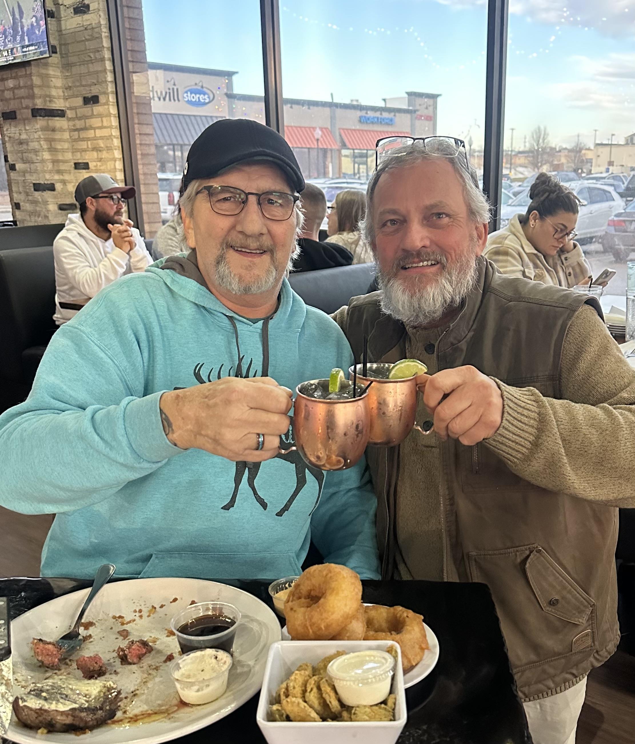 Two men holding cups with food in them