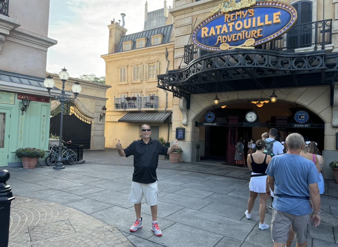 A man is having fun at Remy's Ratatouille Adventure in Epcot. Many people walk by in the background.