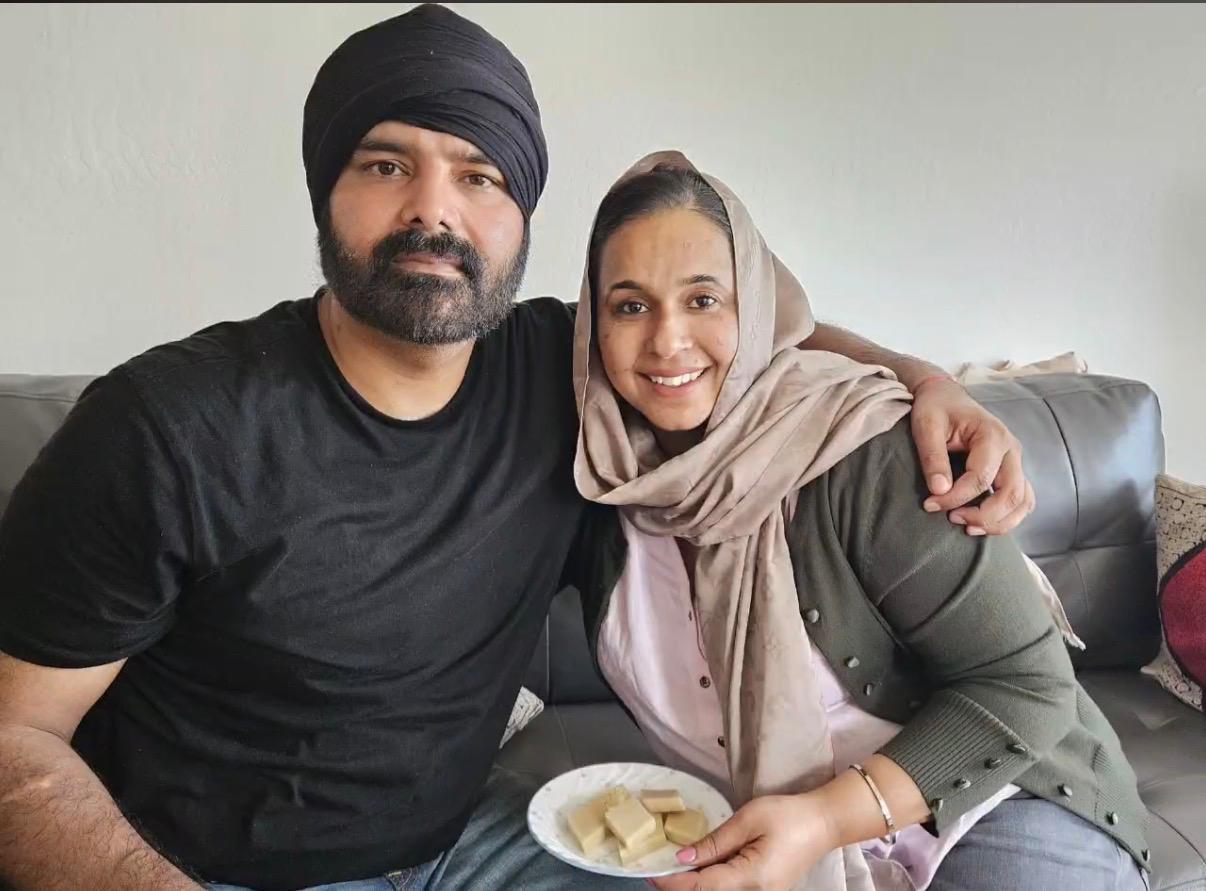 Two friends sit close together on a couch, enjoying snacks and sharing laughter at home.