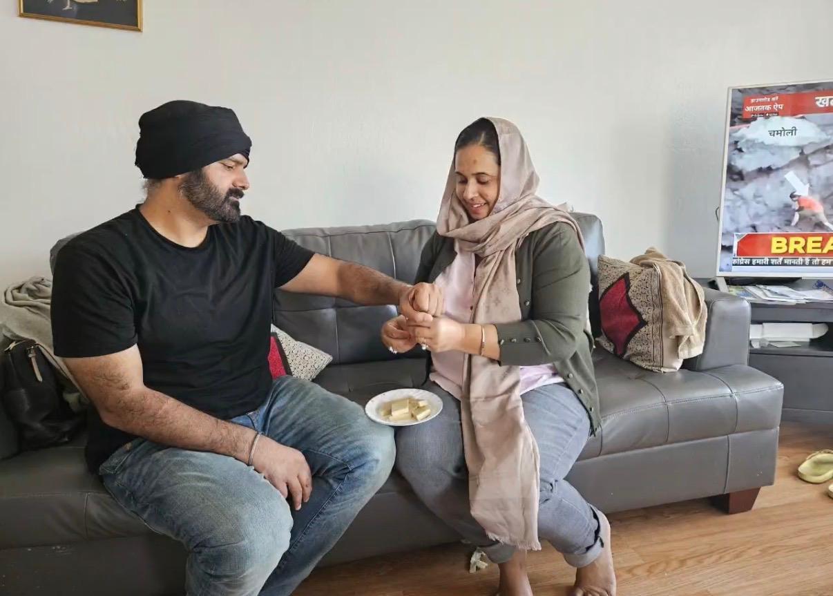 Two friends sit on a couch and enjoy snacks while chatting at home in a casual setting.