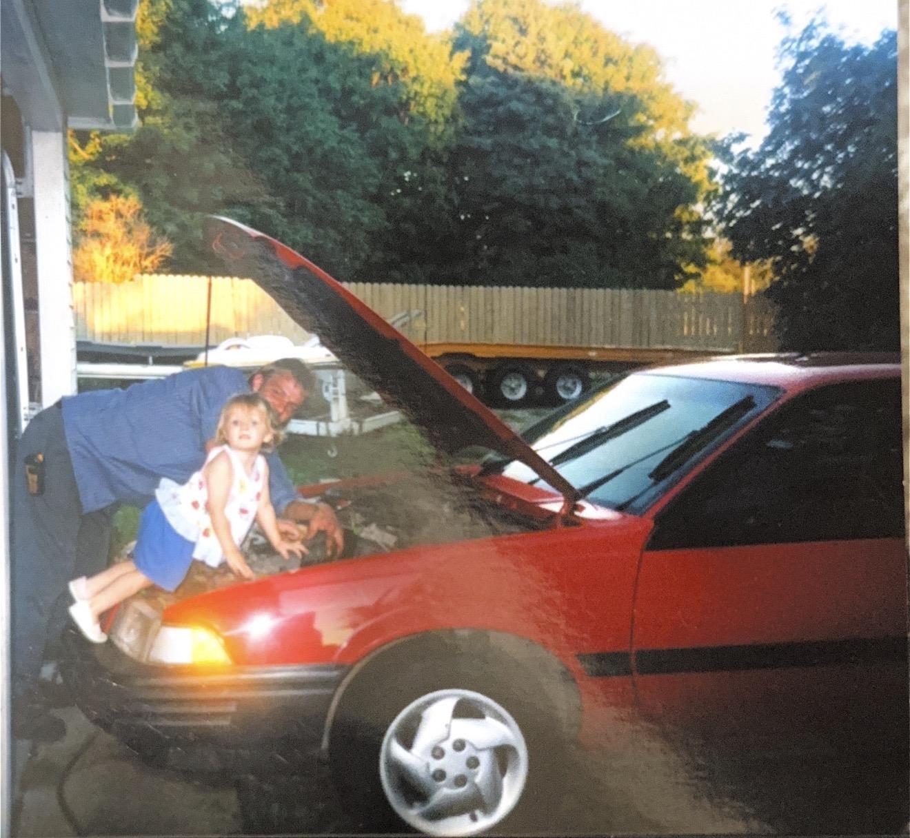 A man and child standing in front of a car