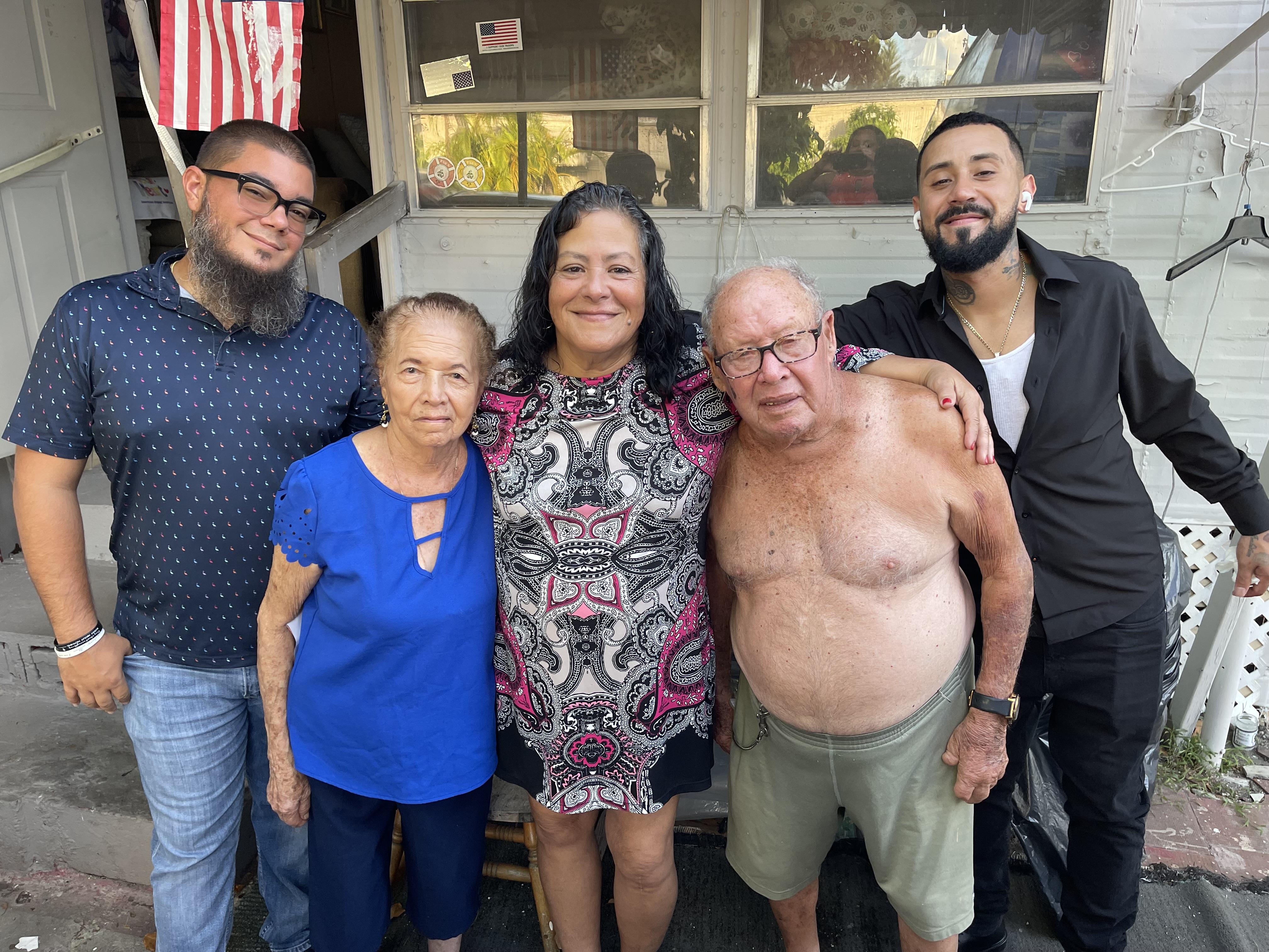 Four family members stand together outside a house smiling for a moment during a family gathering.