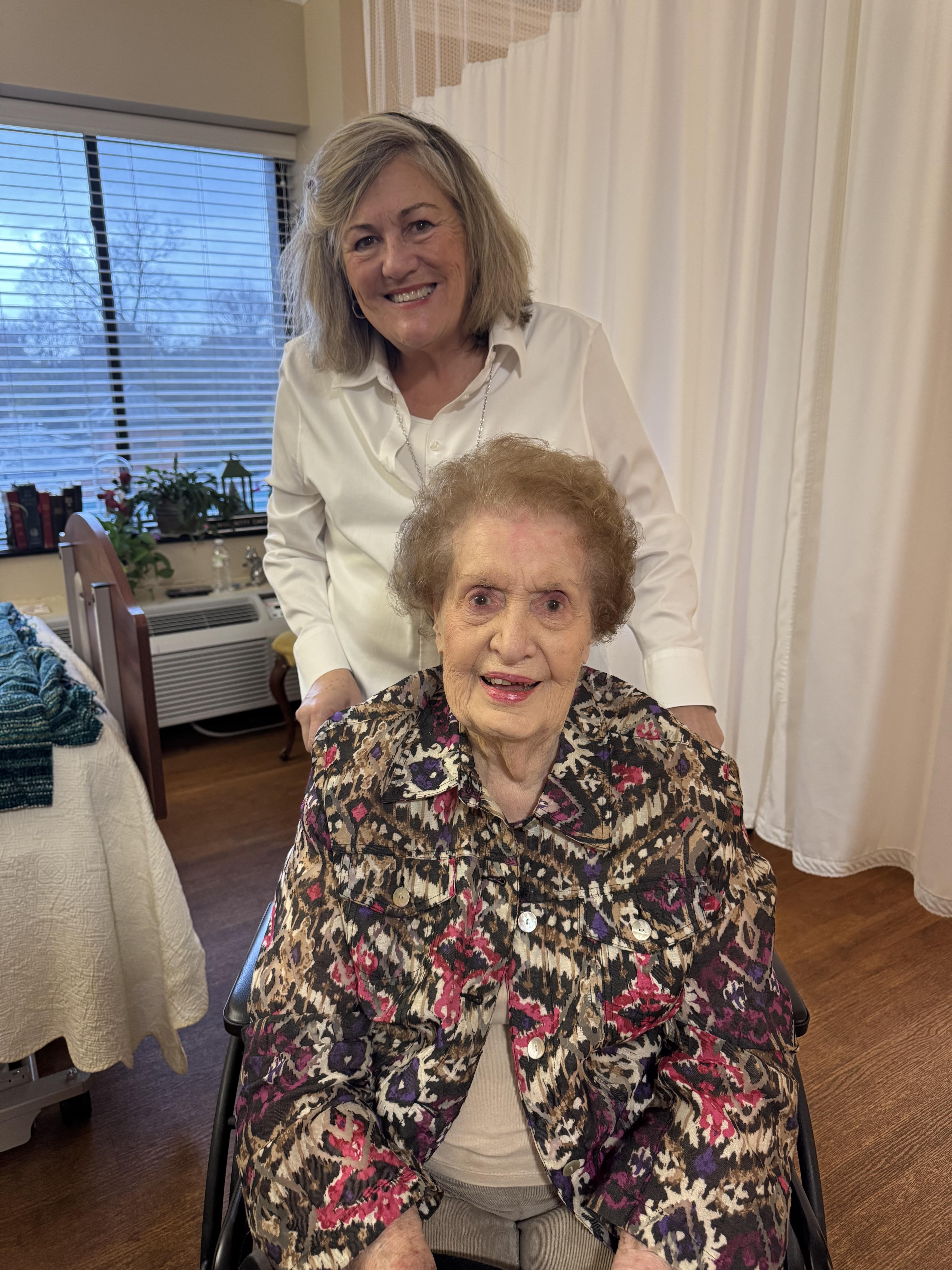 A woman standing next to a woman in a wheelchair