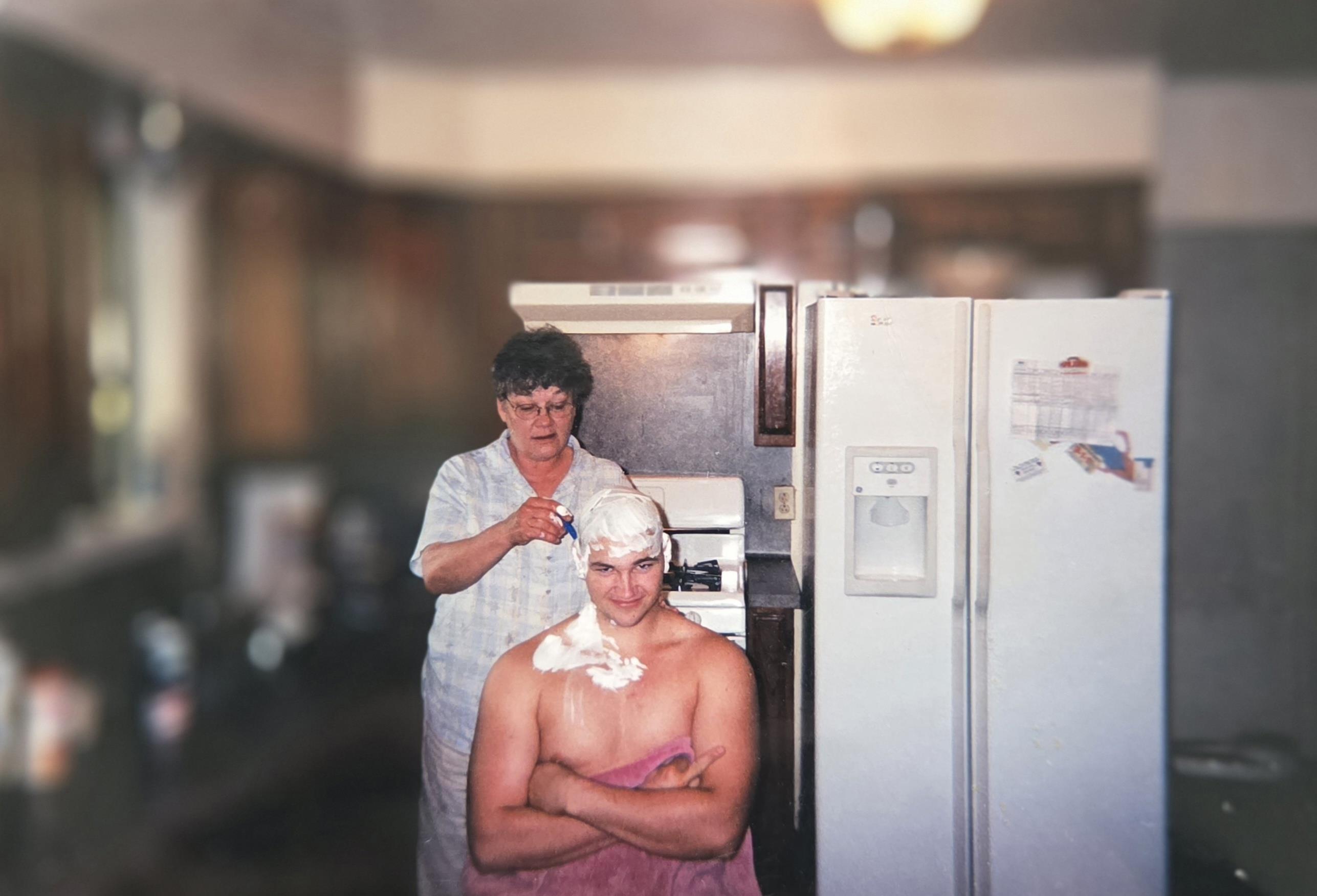 A woman shaving a man's head