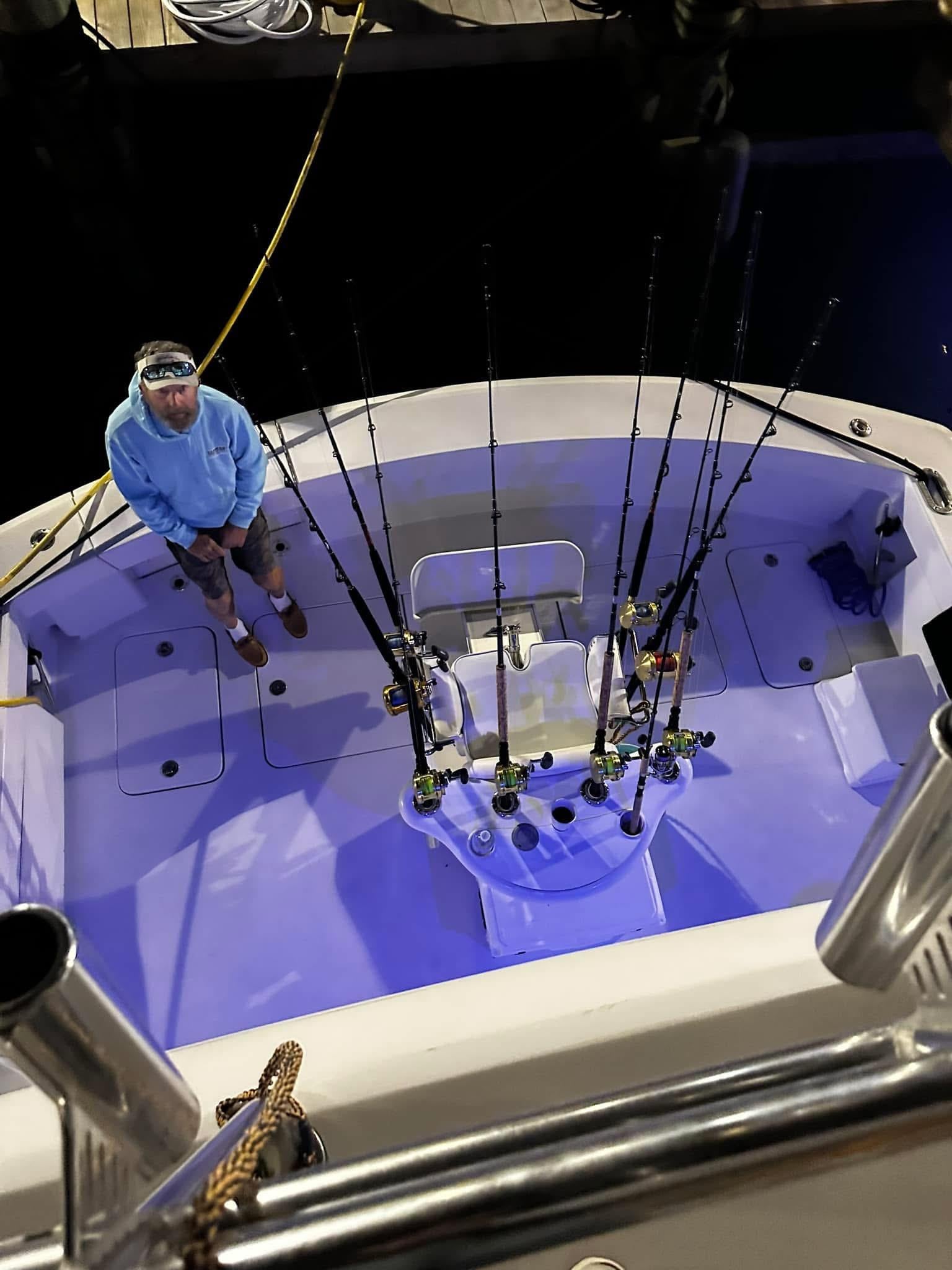 A man sitting on a boat with fishing poles
