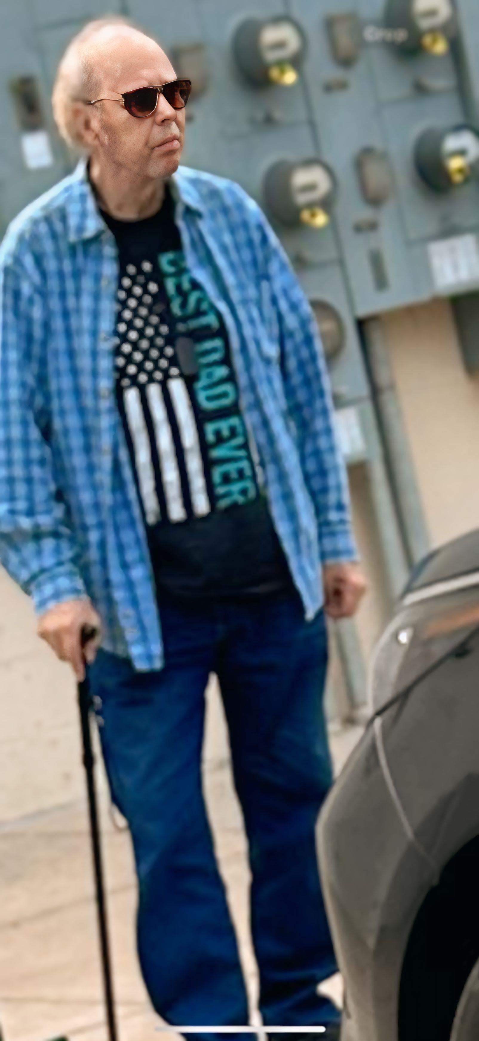 A man wearing a blue plaid shirt and blue jeans