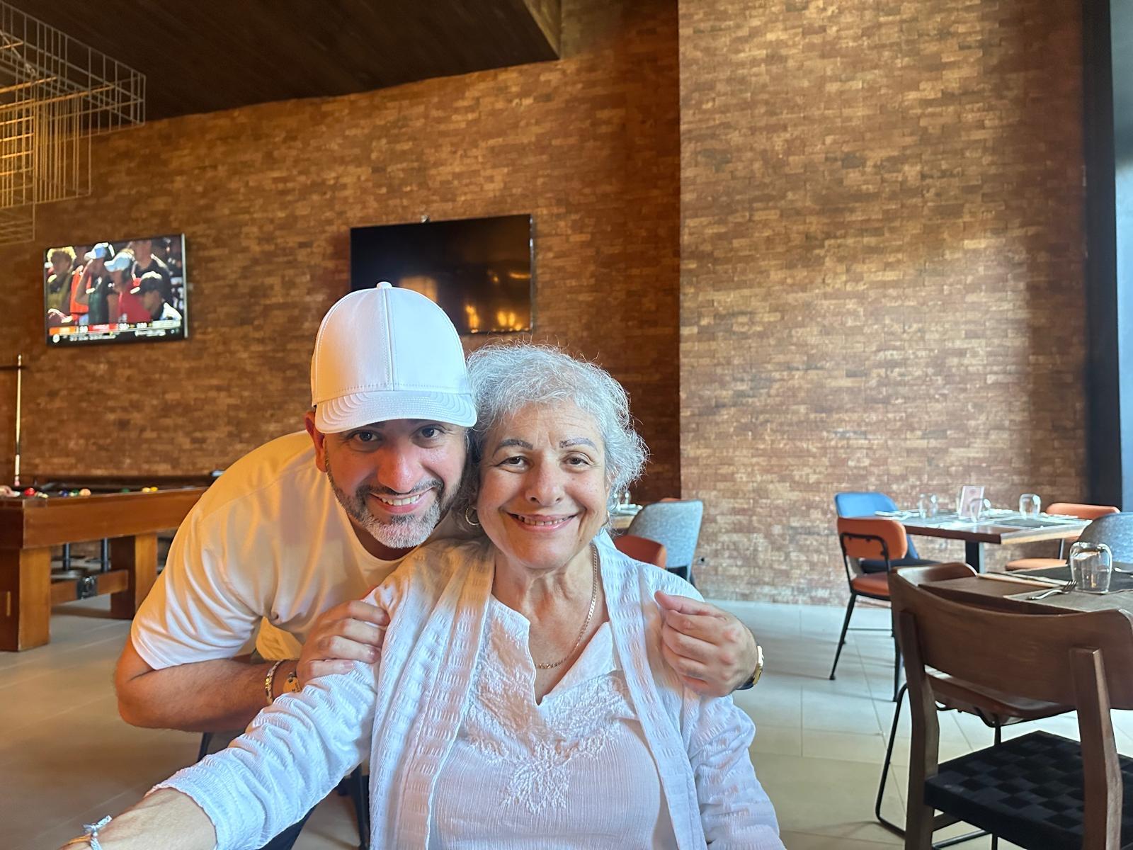 Two individuals smile in a restaurant setting while sharing a lighthearted moment.