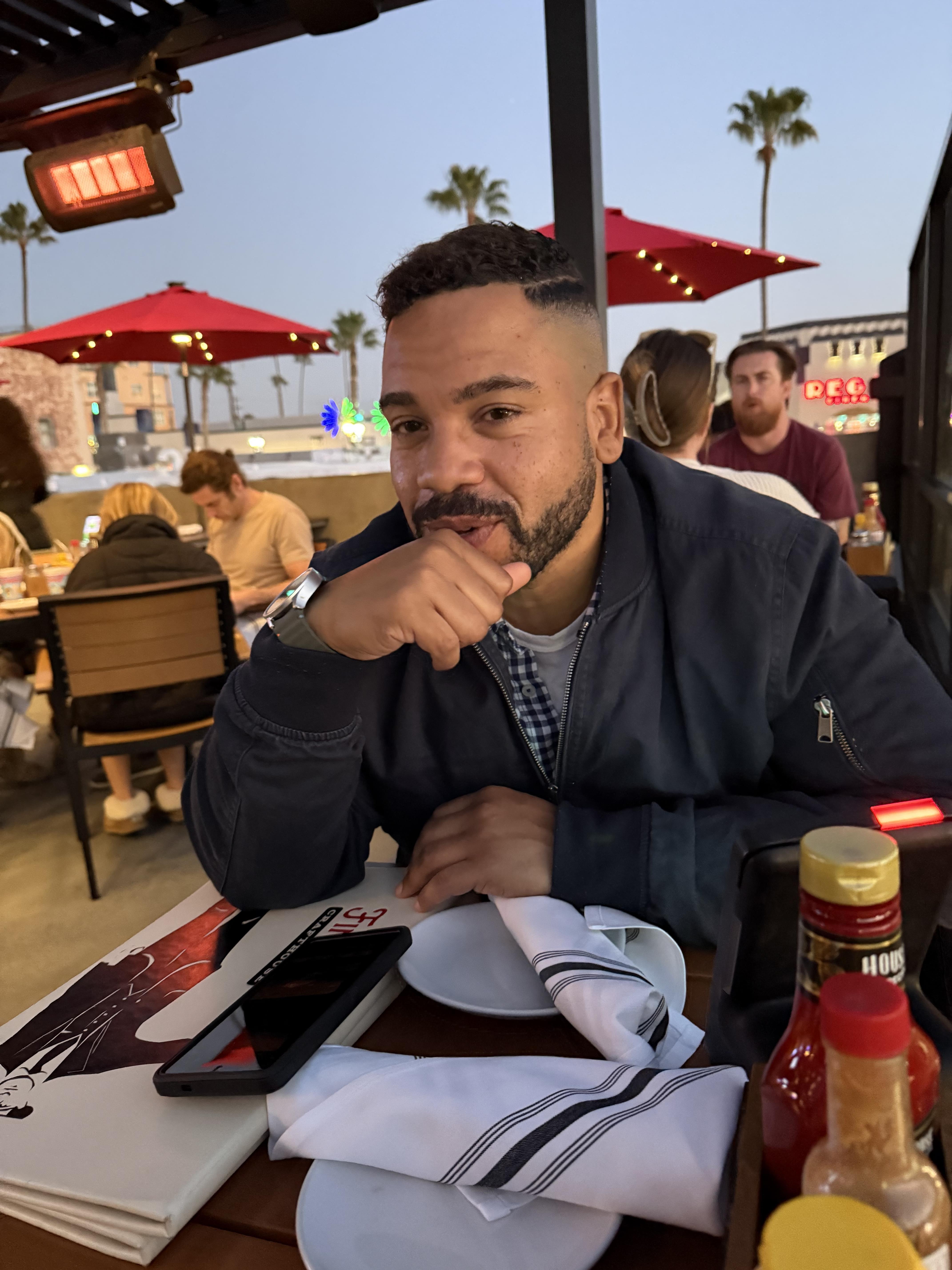 A man sitting at a table with a plate and a phone