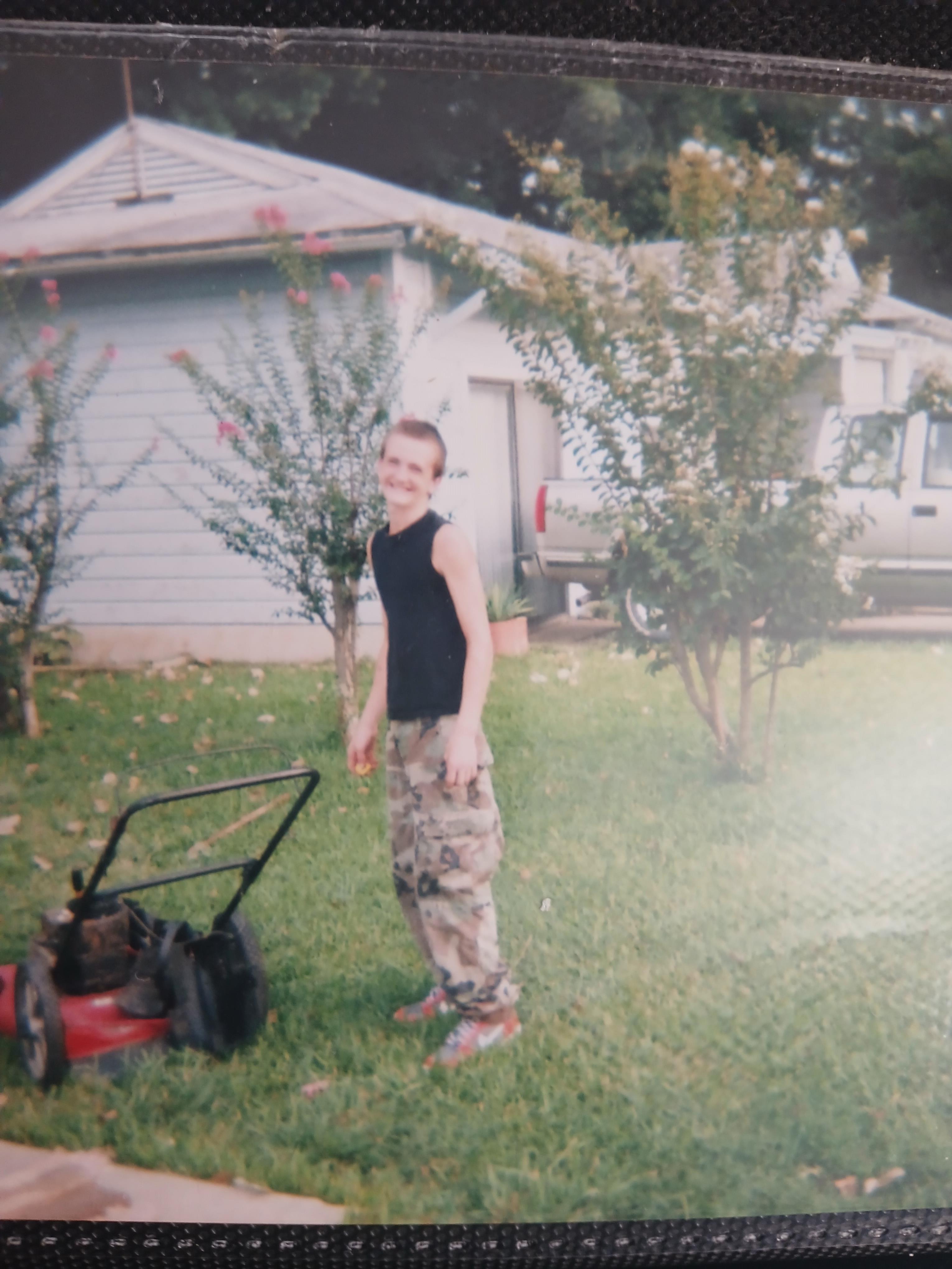 A person standing in a yard with a lawnmower