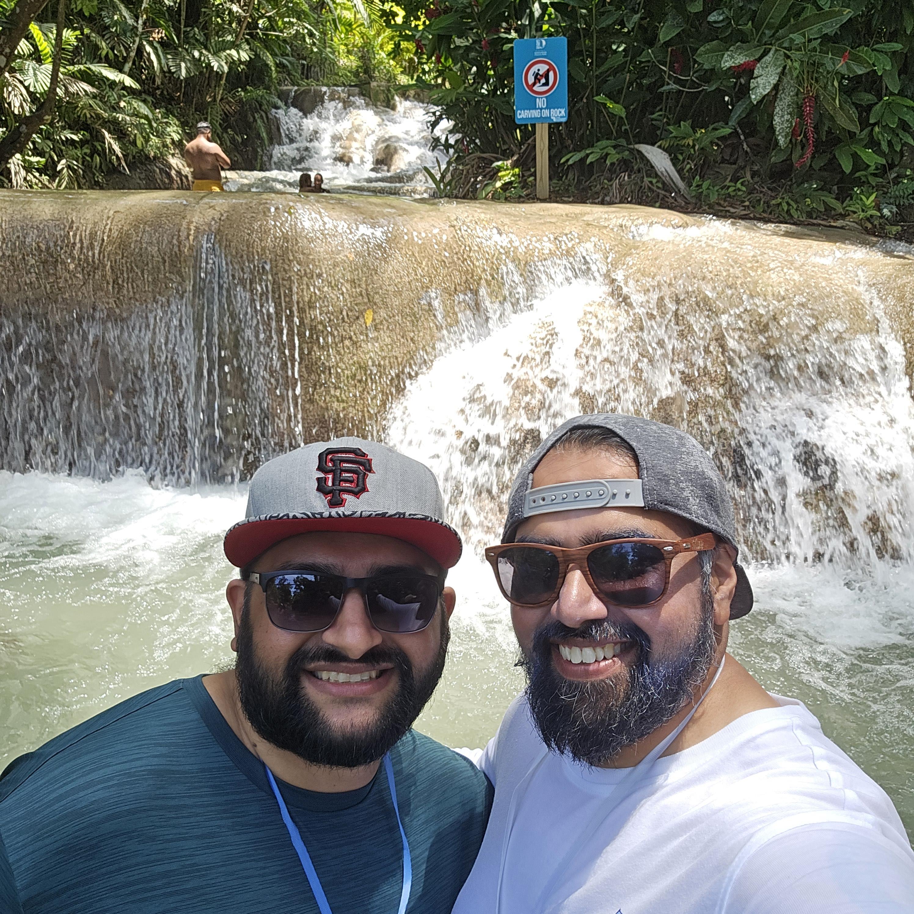 Two men taking a selfie in front of a waterfall