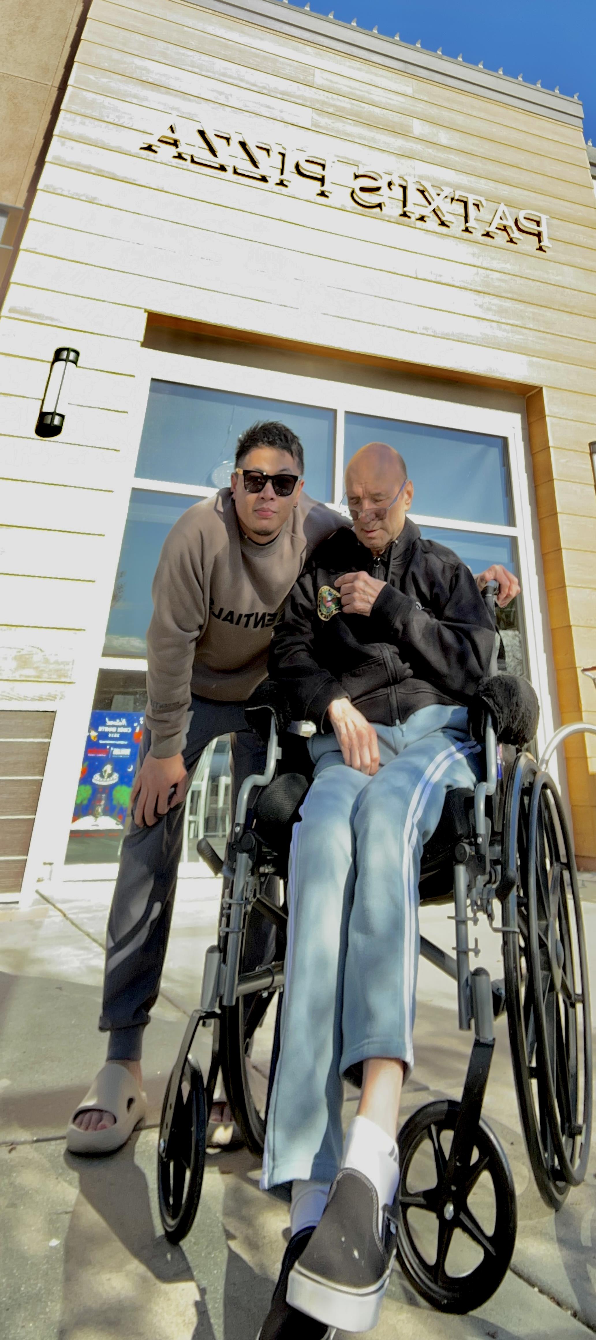 A man standing next to a man in a wheelchair