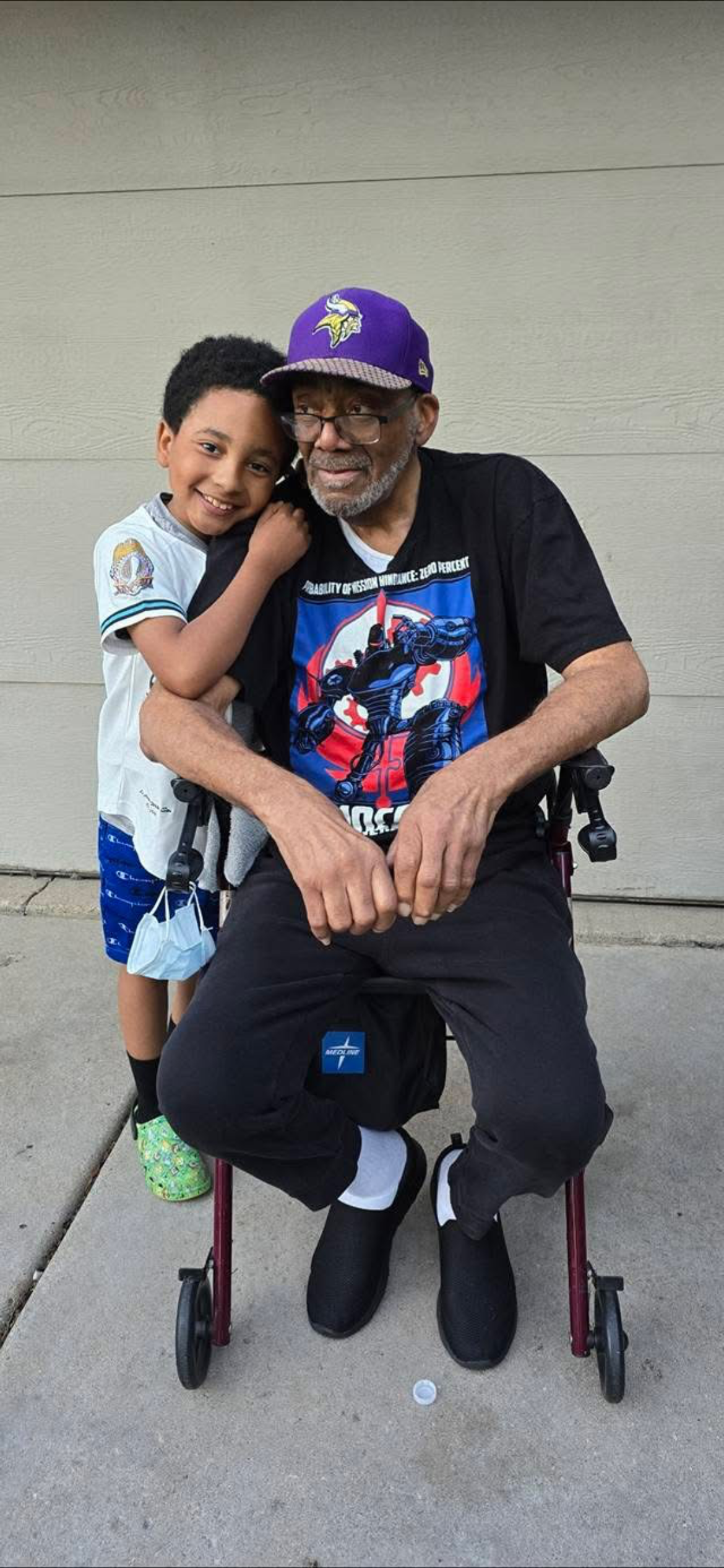 A man and boy sitting on a wheelchair