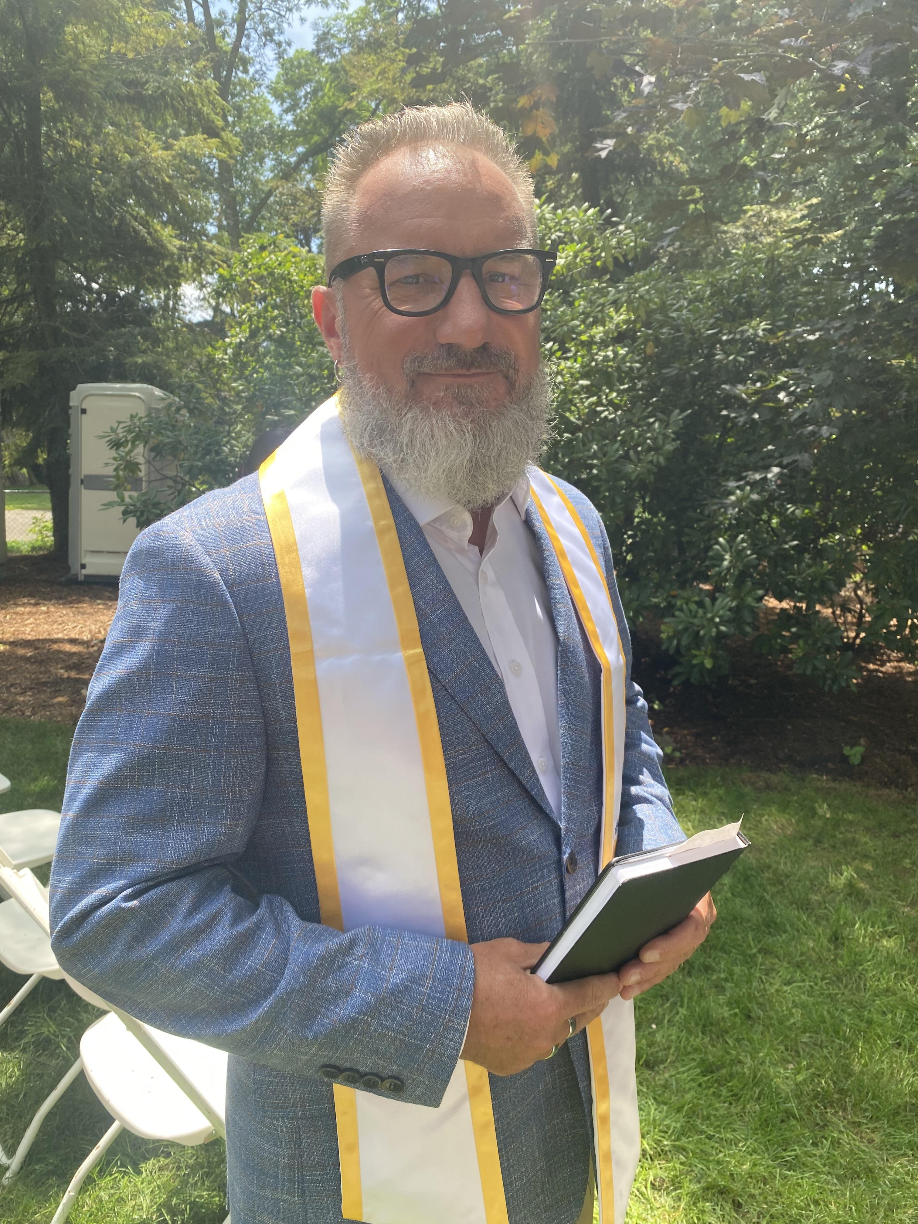 A man wearing glasses and a blue suit holding a book