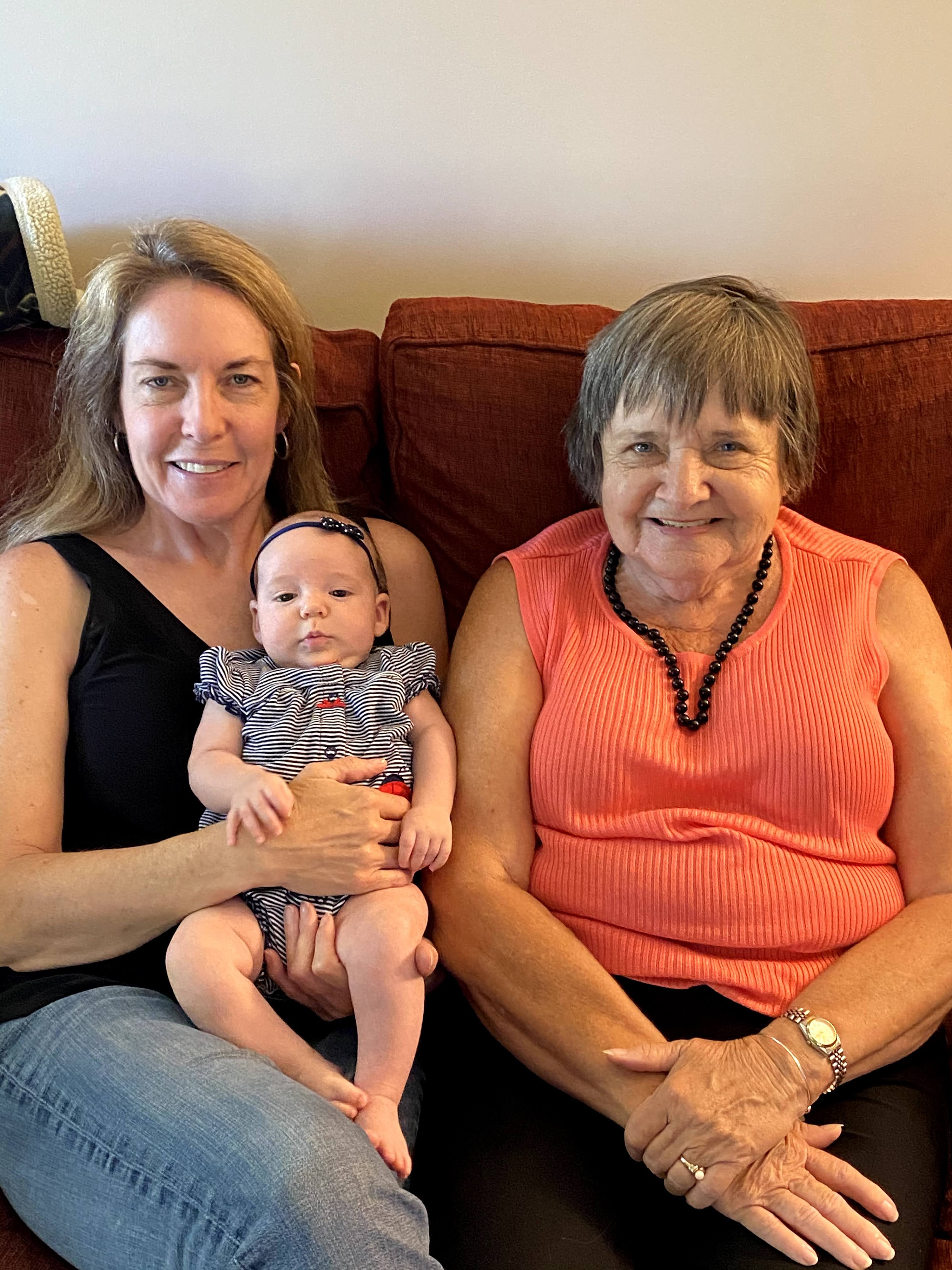 A group of women sitting on a couch with a baby