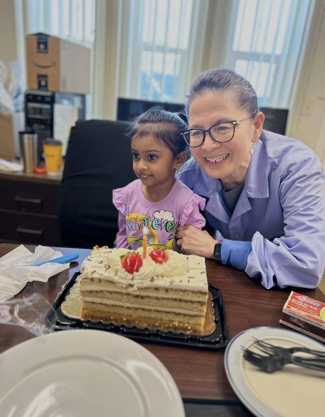 A woman and a girl sitting at a table with a cake
