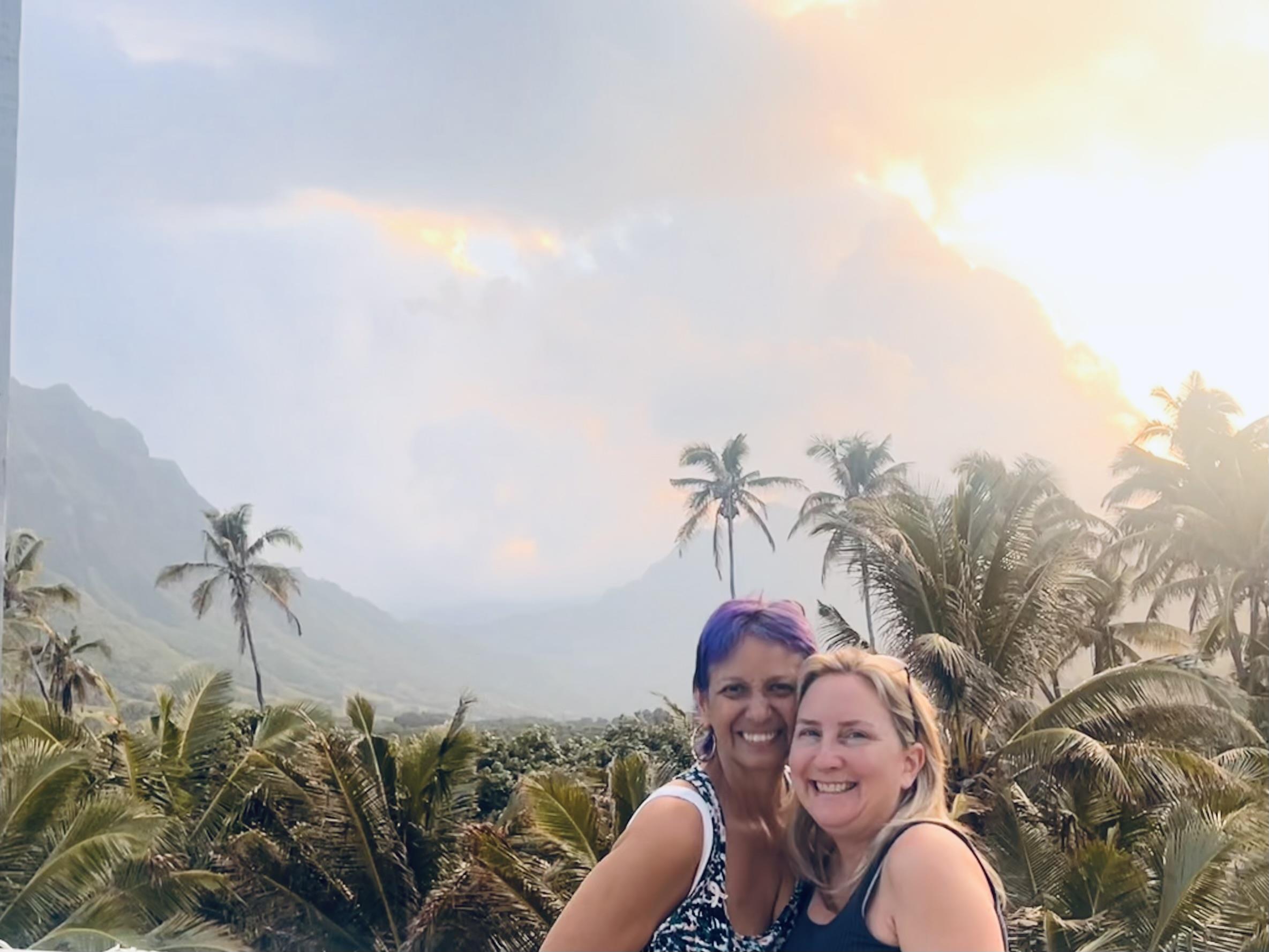 Two women taking a selfie in front of palm trees