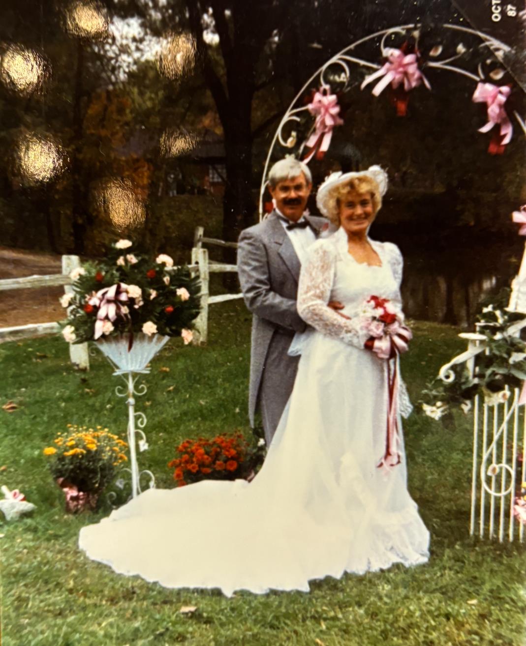 A man and woman standing in front of a wedding arch