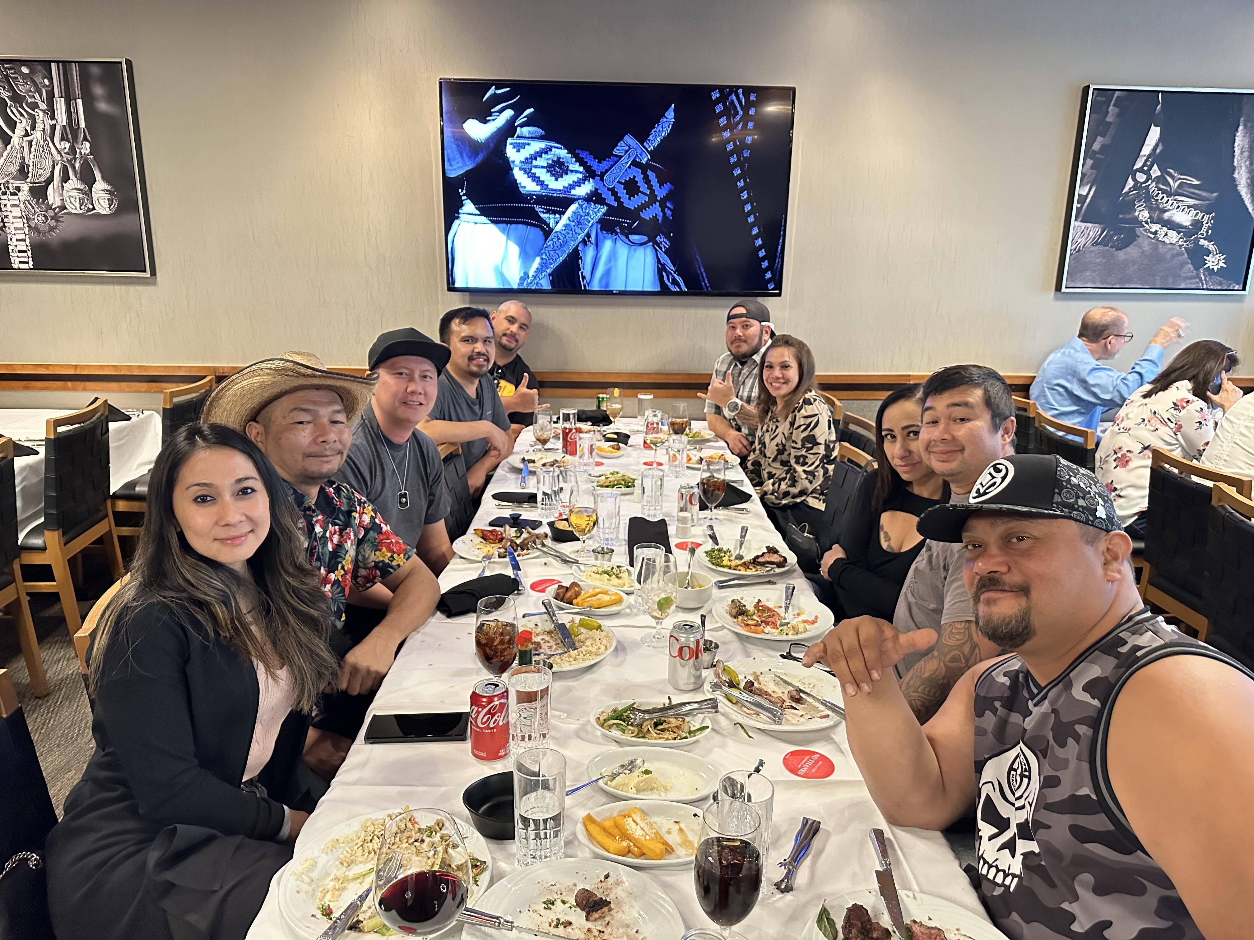 A group of people sitting at a long table with food