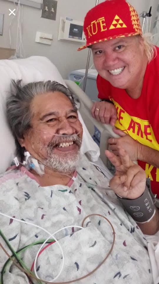A man in a hospital bed with a woman in a red shirt