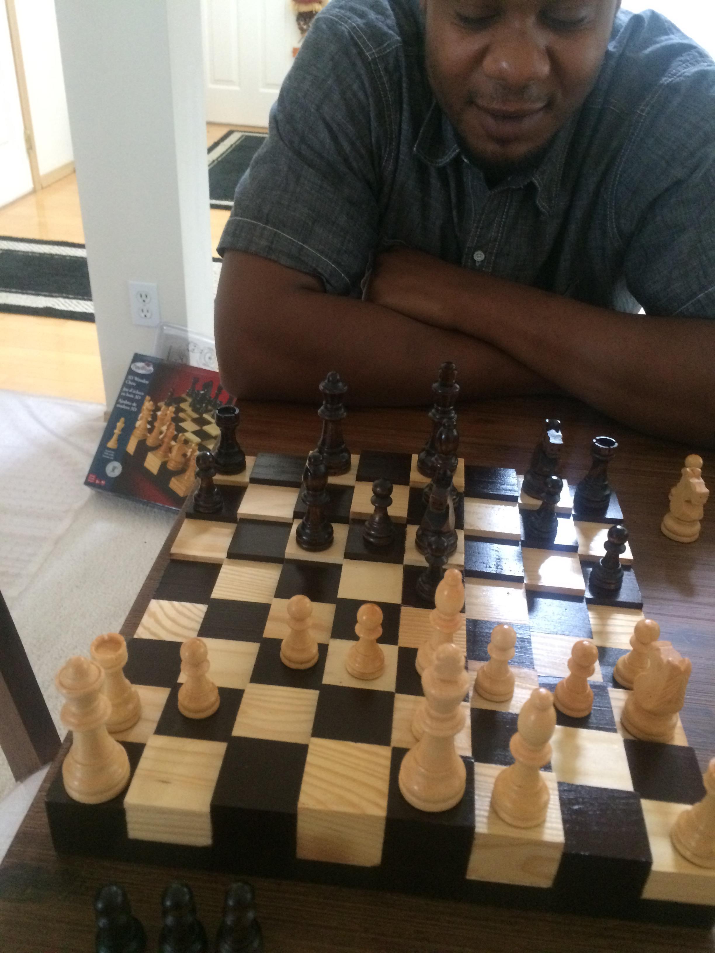 A man sitting at a table with chess pieces