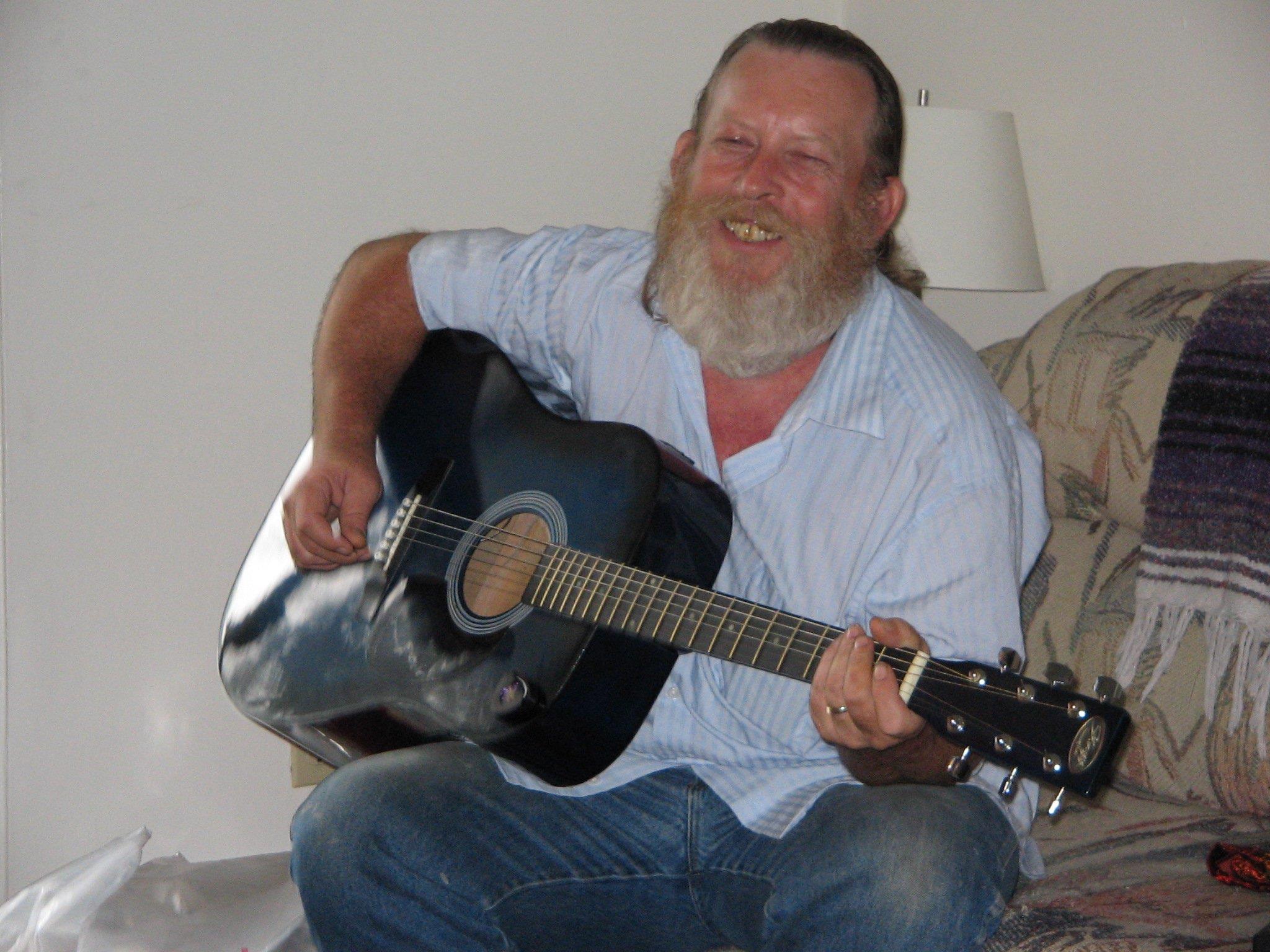A man sitting on a couch playing a guitar