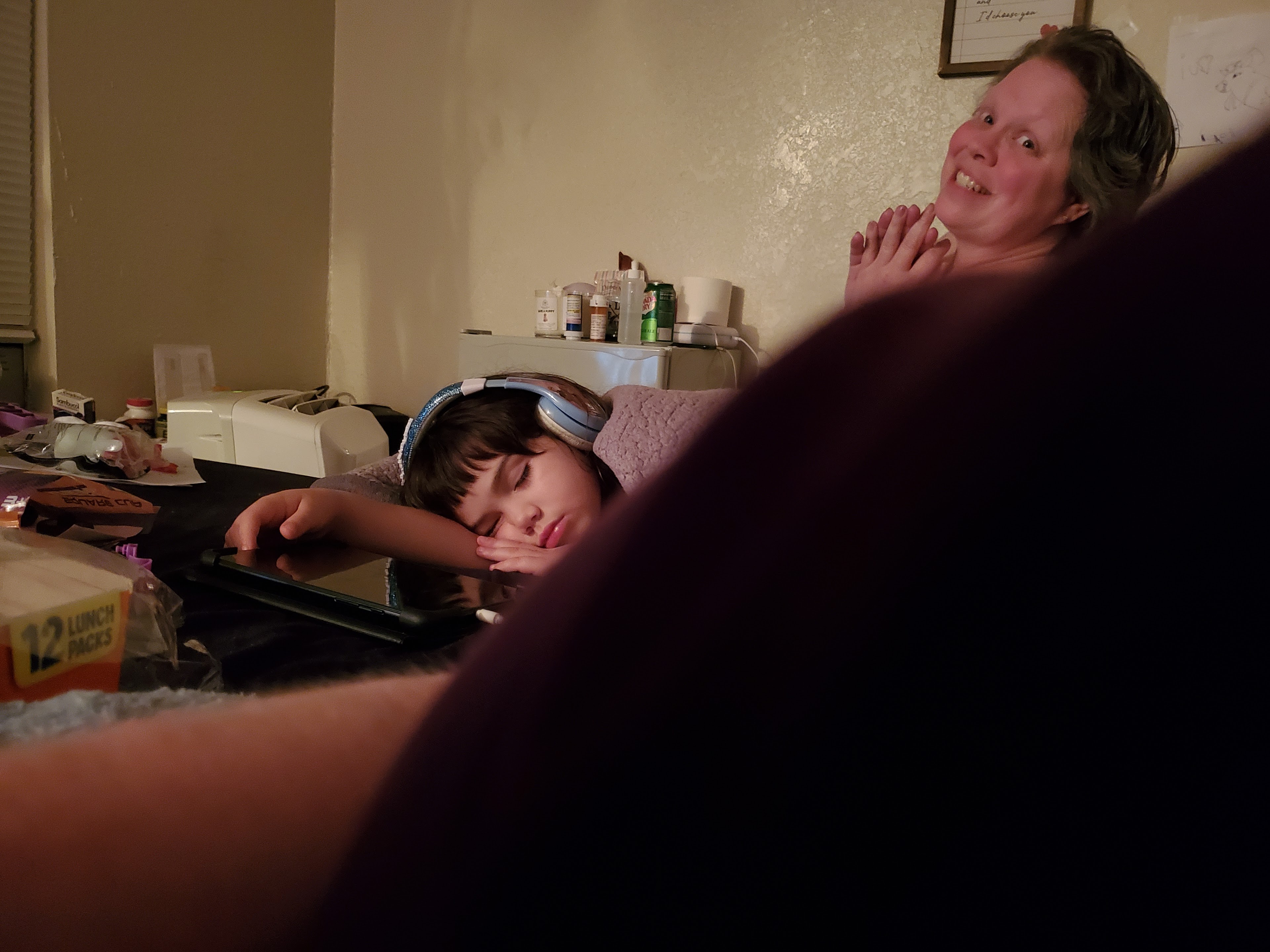 A boy with headphones on and a woman with a tablet
