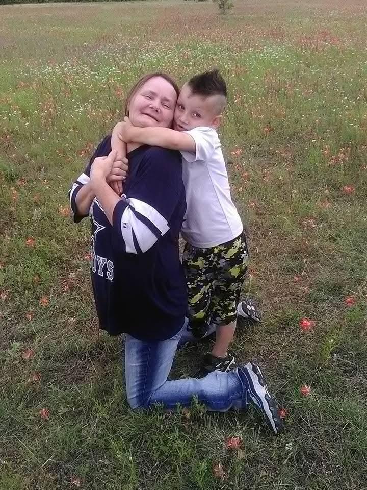 A woman and a boy hugging in a field