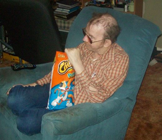 A man sitting in a chair with a bag of chips